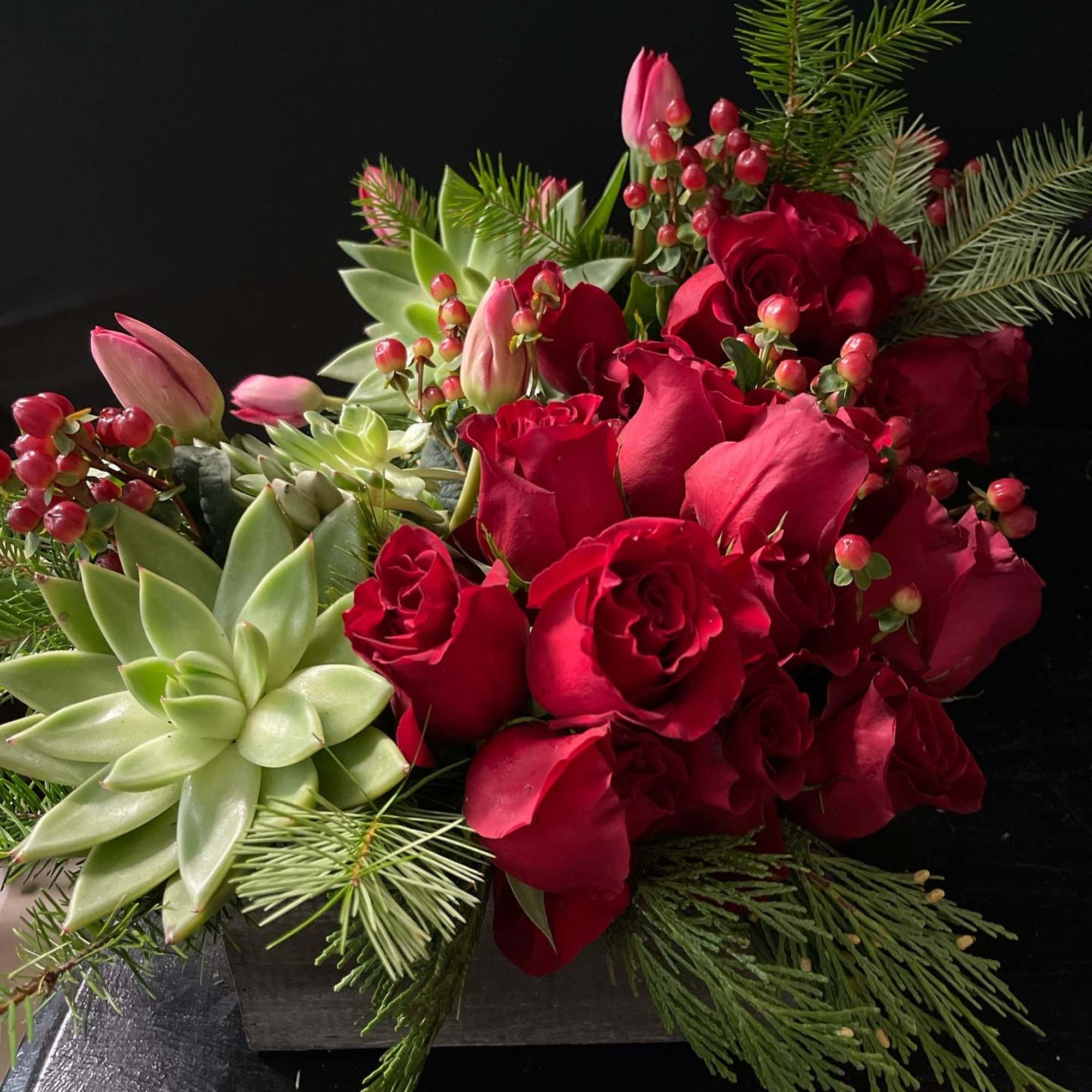 Beautiful red rose design with succulents and Christmas greens. 