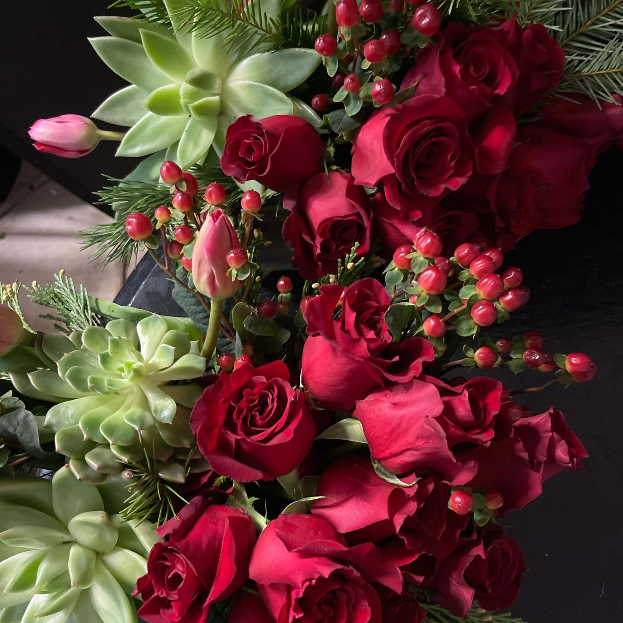 Beautiful red rose design with succulents and Christmas greens. 