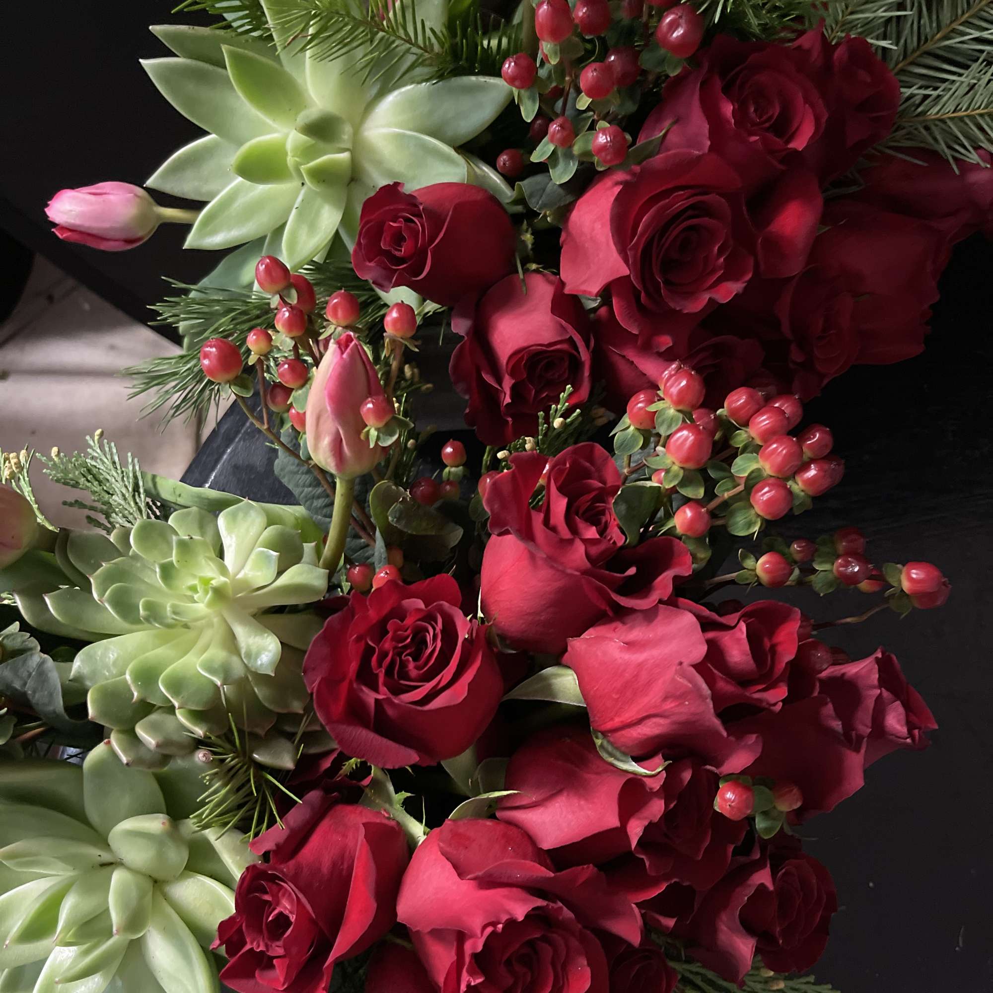 Beautiful red rose design with succulents and Christmas greens. 