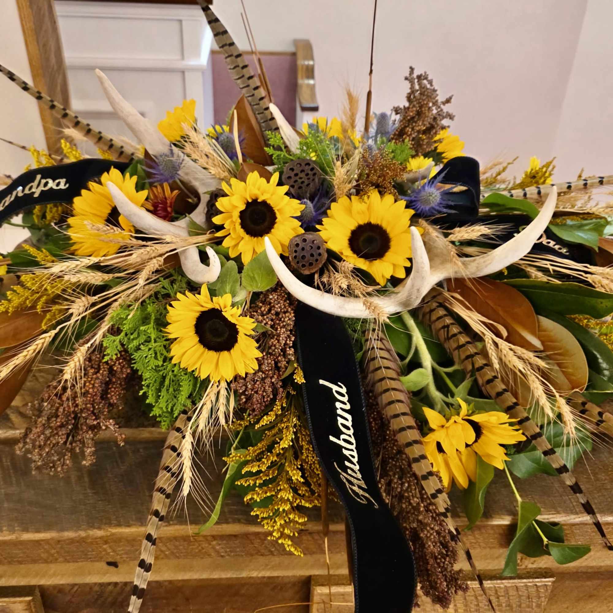 Sunflowers, natural grevellia, vyking mums, cattails and craspedia with pheasant feathers and