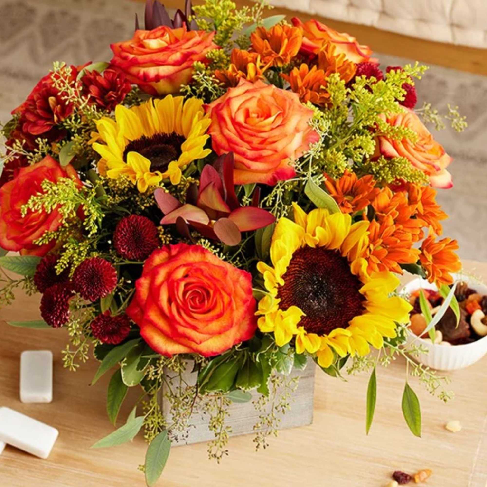 All-around arrangement with red button poms and leucadendrons, autumn-color roses, sunflowers, and