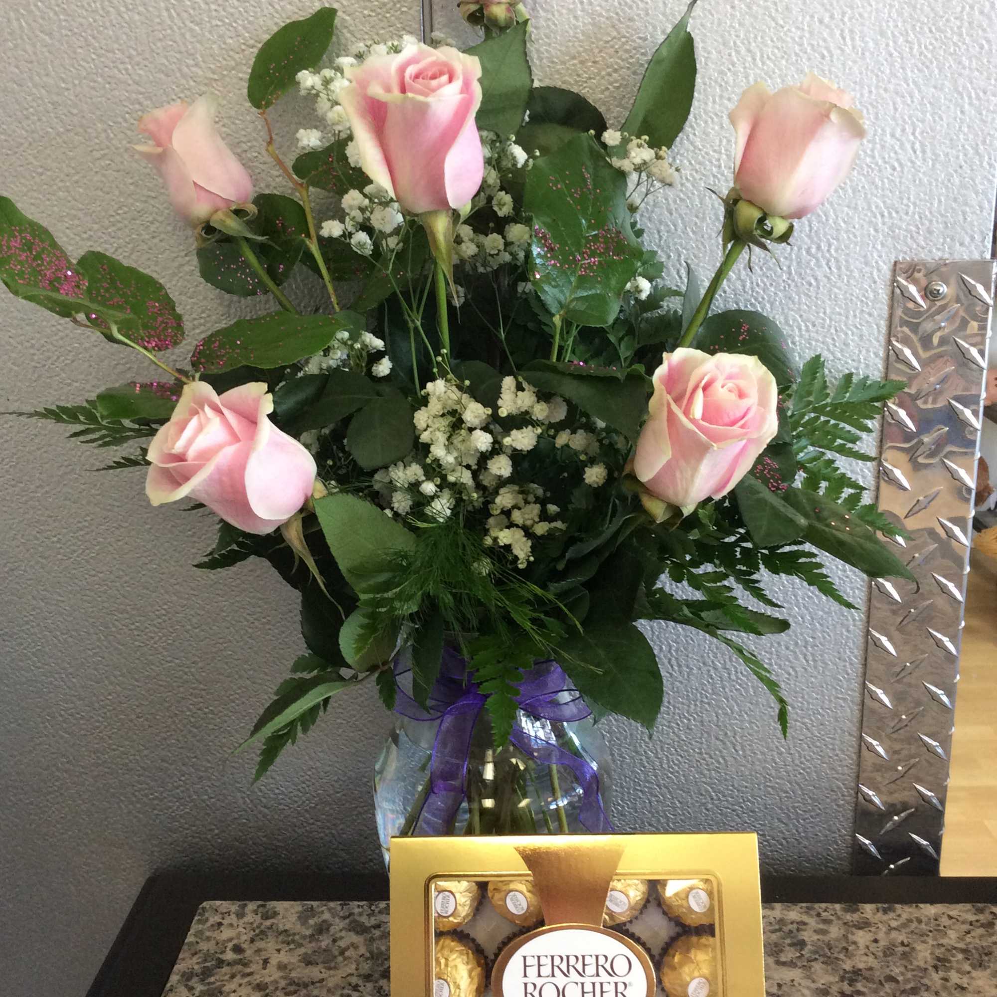 6 light pink roses in a glass vase with sparkly leaves. Chocolates