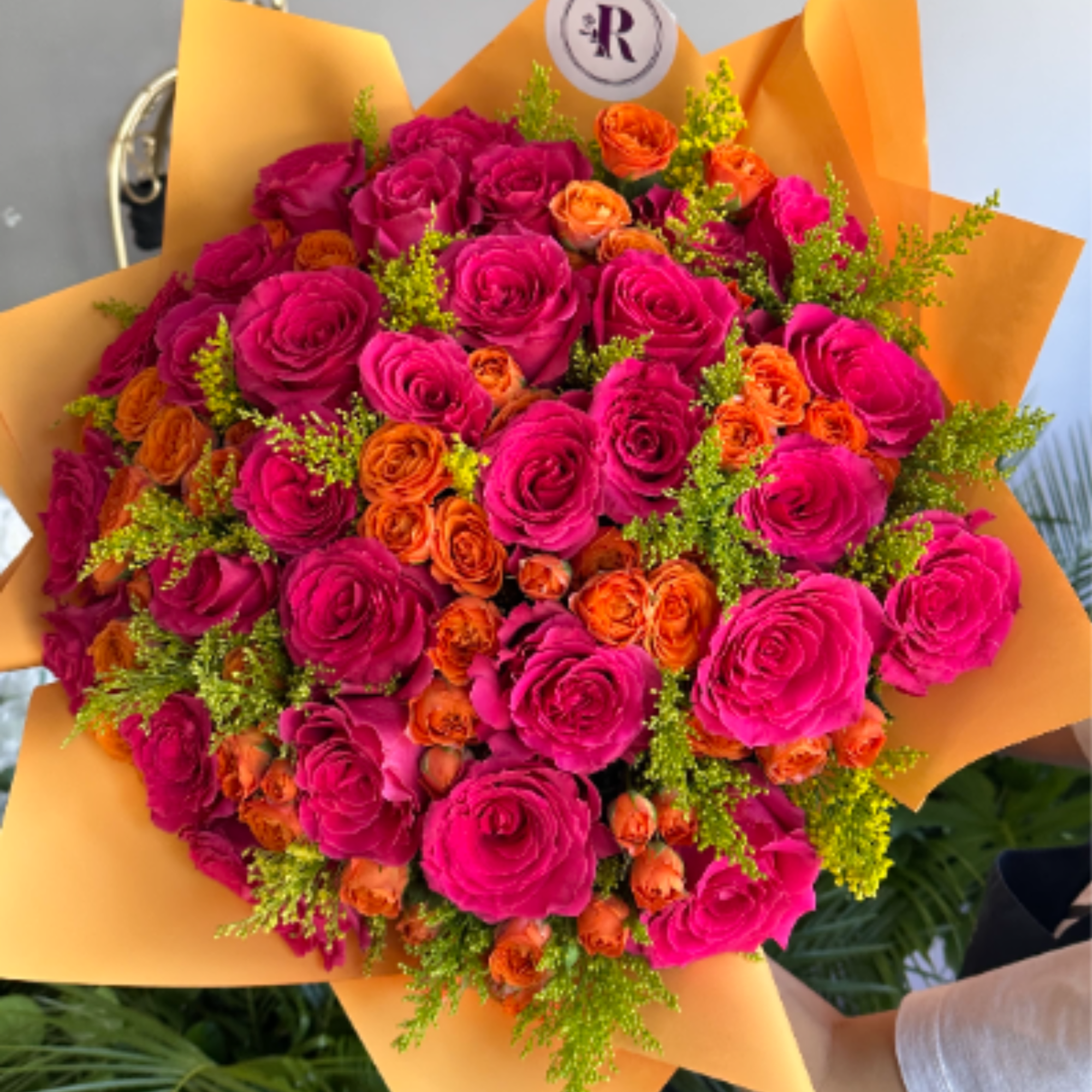 A radiant fall bouquet featuring fuchsia colored and orange roses, golden solidago
