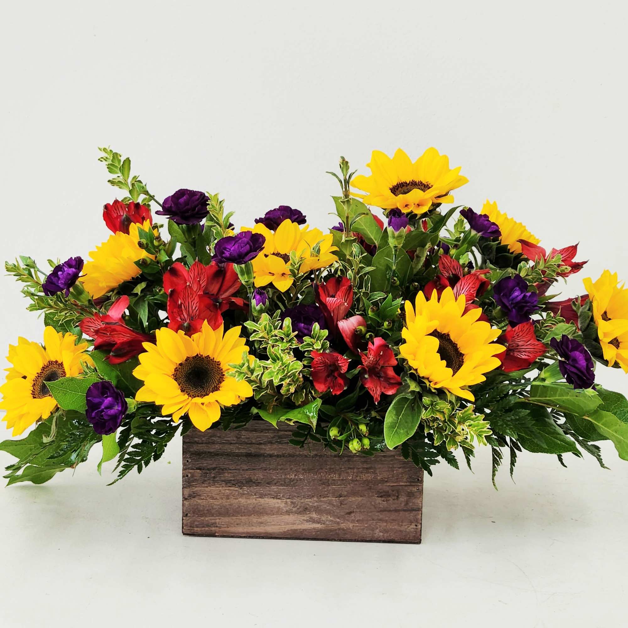 A cheerful blend of radiant sunflowers, soft spray roses, and vibrant red