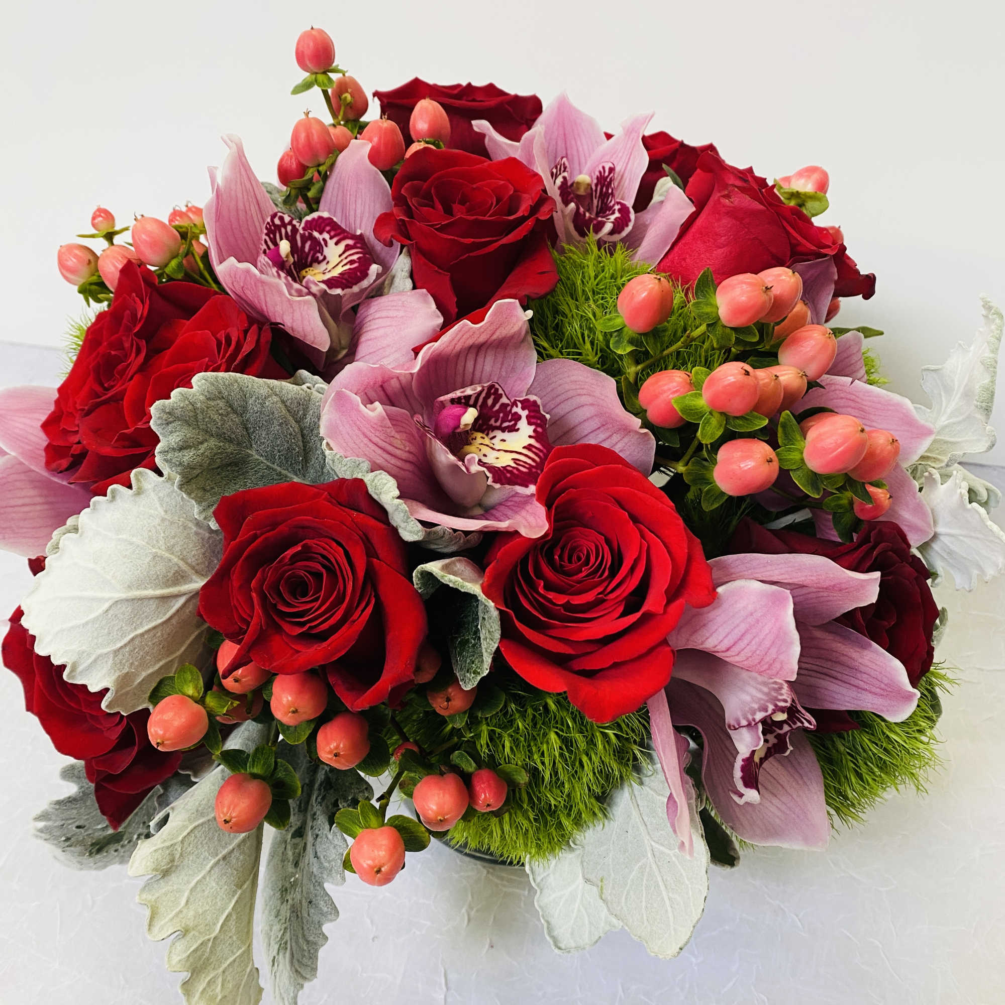 Beautiful arrangement in a glass vase with red roses, , pink cymbidium