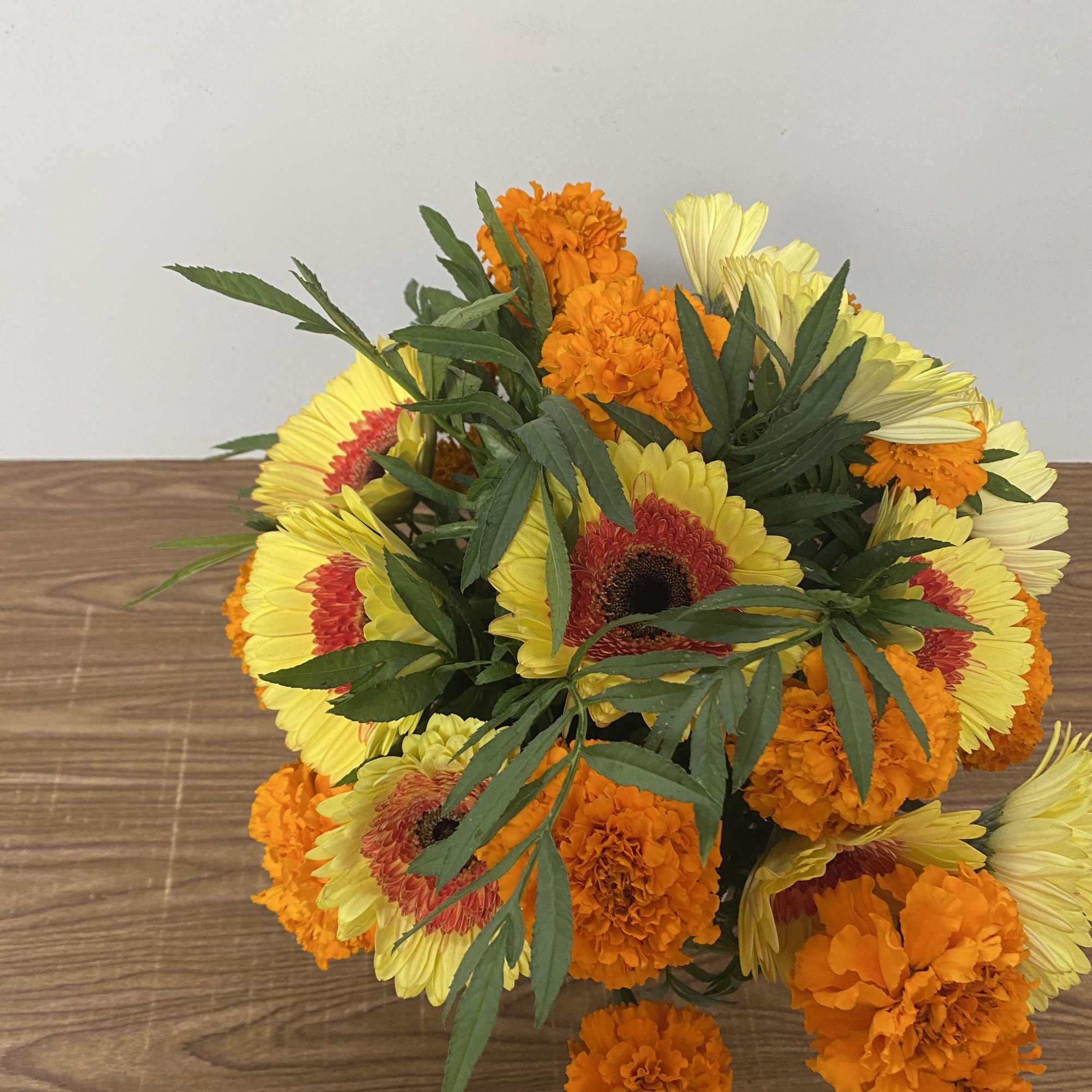 In a glass vase Combination of orange  Marigold and yellow Gerber&rsquo;s