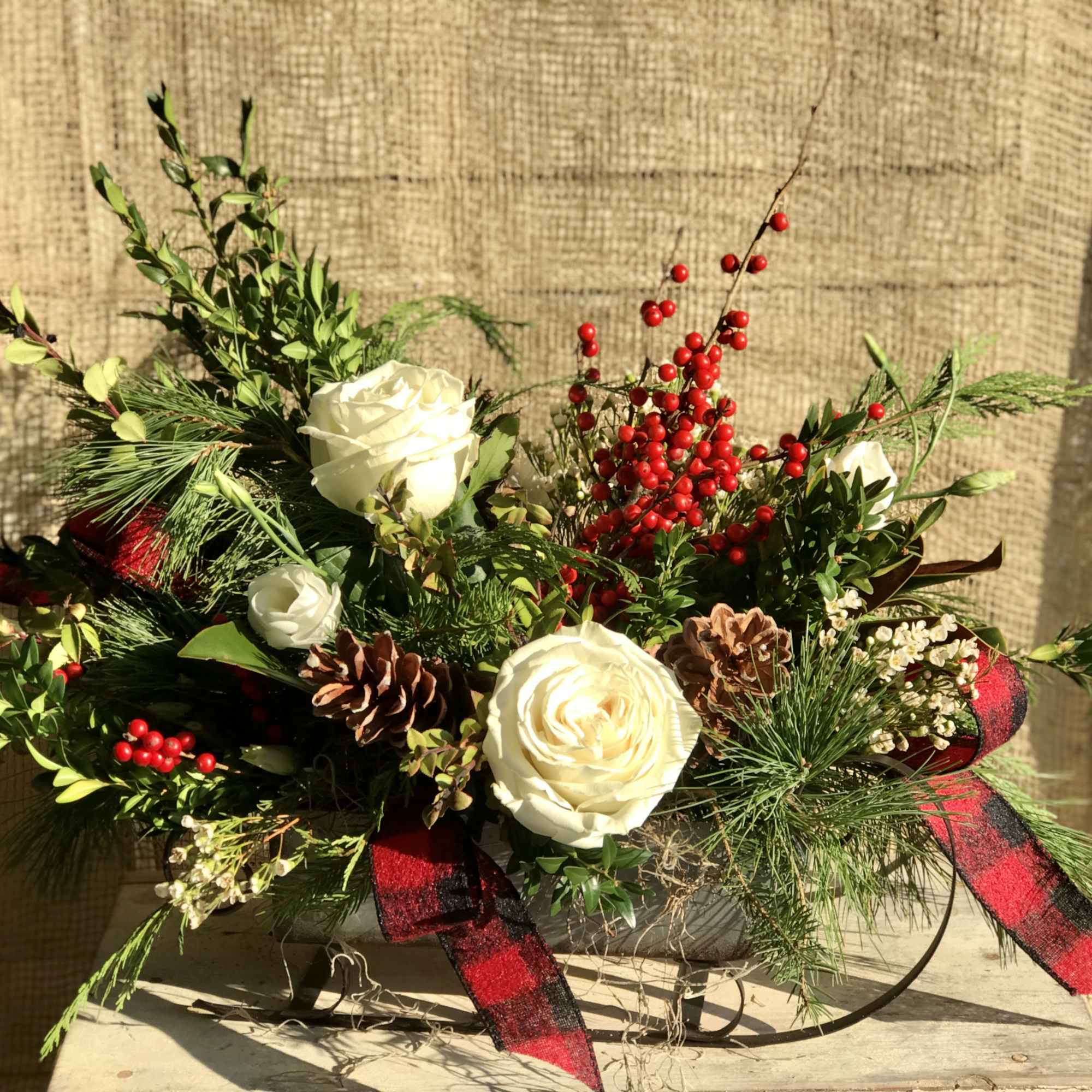 This metal sleigh carries an assortment of fragrant evergreens, assorted red and