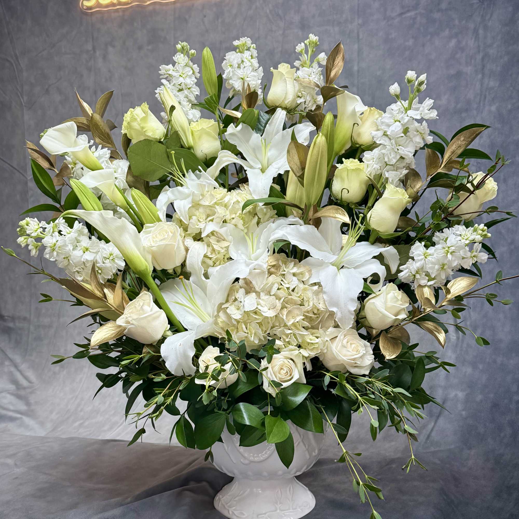 Elegant White Gold Urn . This arrangement features striking white lilies 