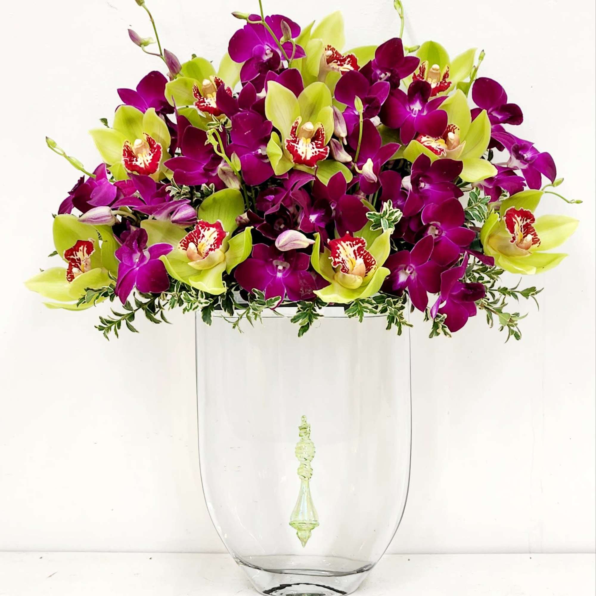 A luxurious fall arrangement of green and deep purple orchids, gracefully floating