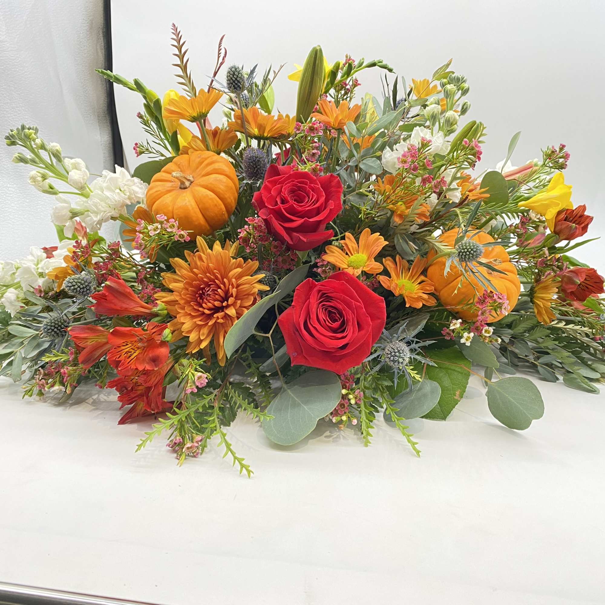 This floral creation has seasonal hints and tones of oranges and reds....