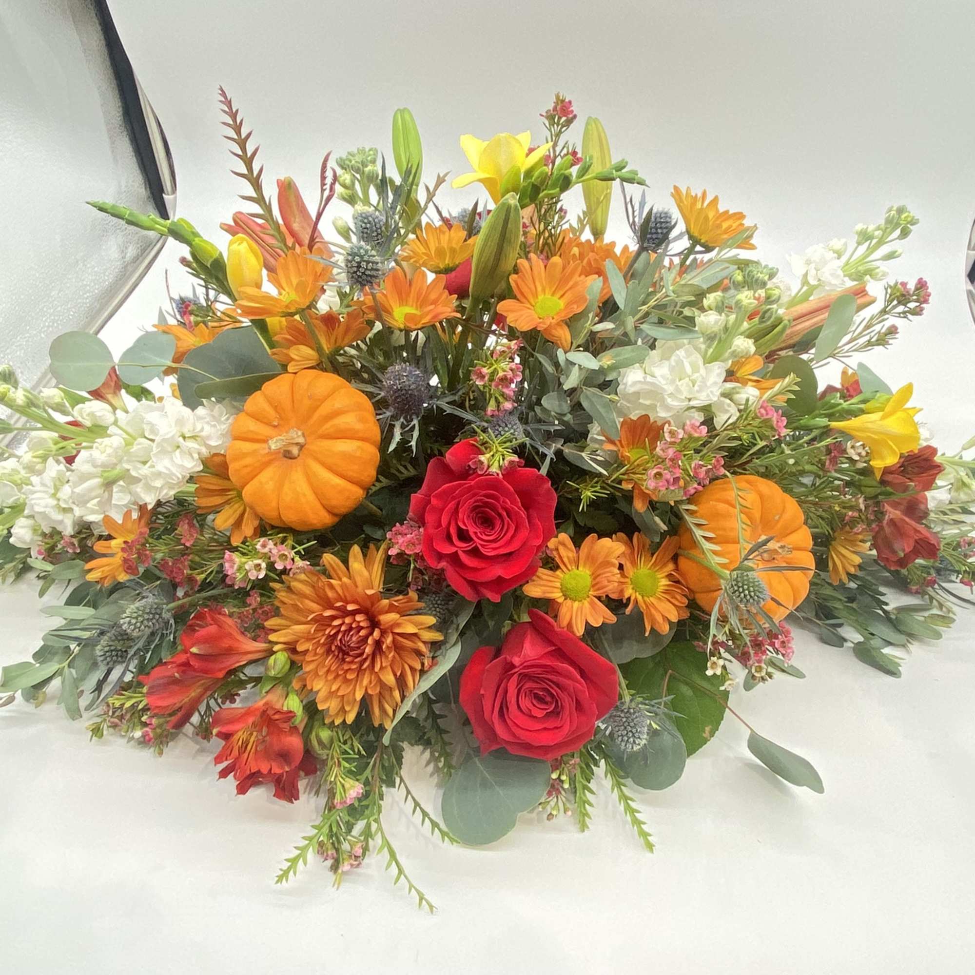 This floral creation has seasonal hints and tones of oranges and reds....