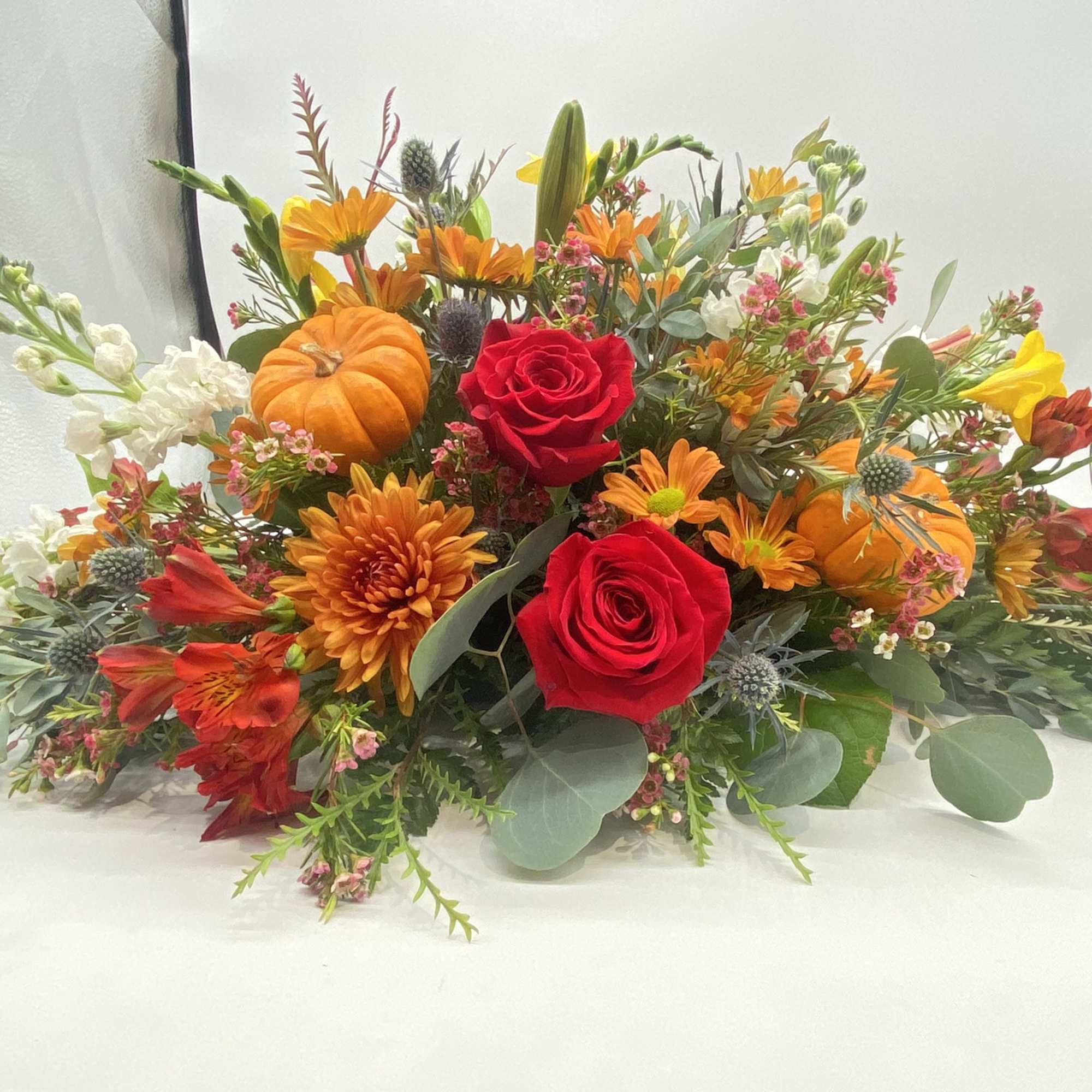 This floral creation has seasonal hints and tones of oranges and reds....