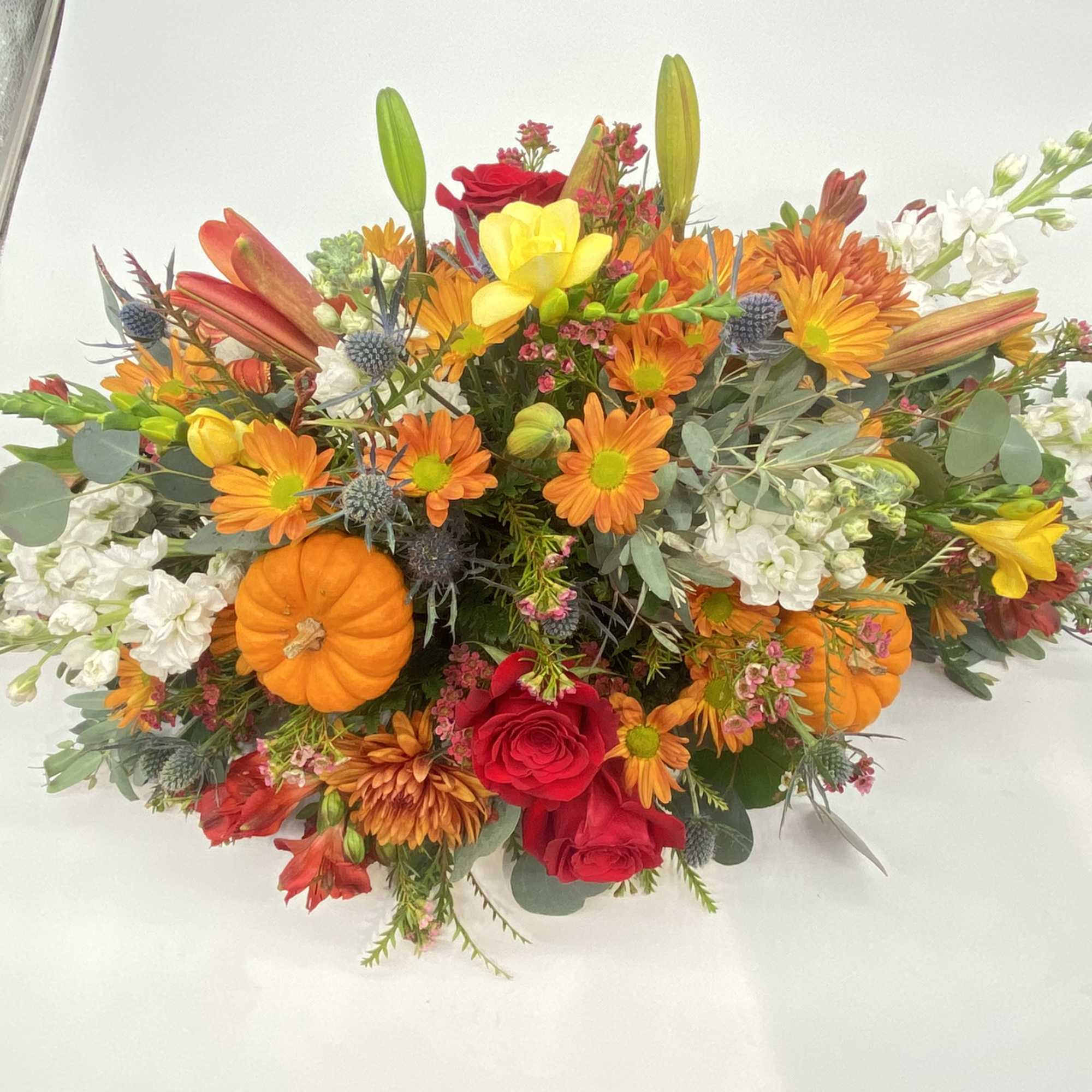 This floral creation has seasonal hints and tones of oranges and reds....