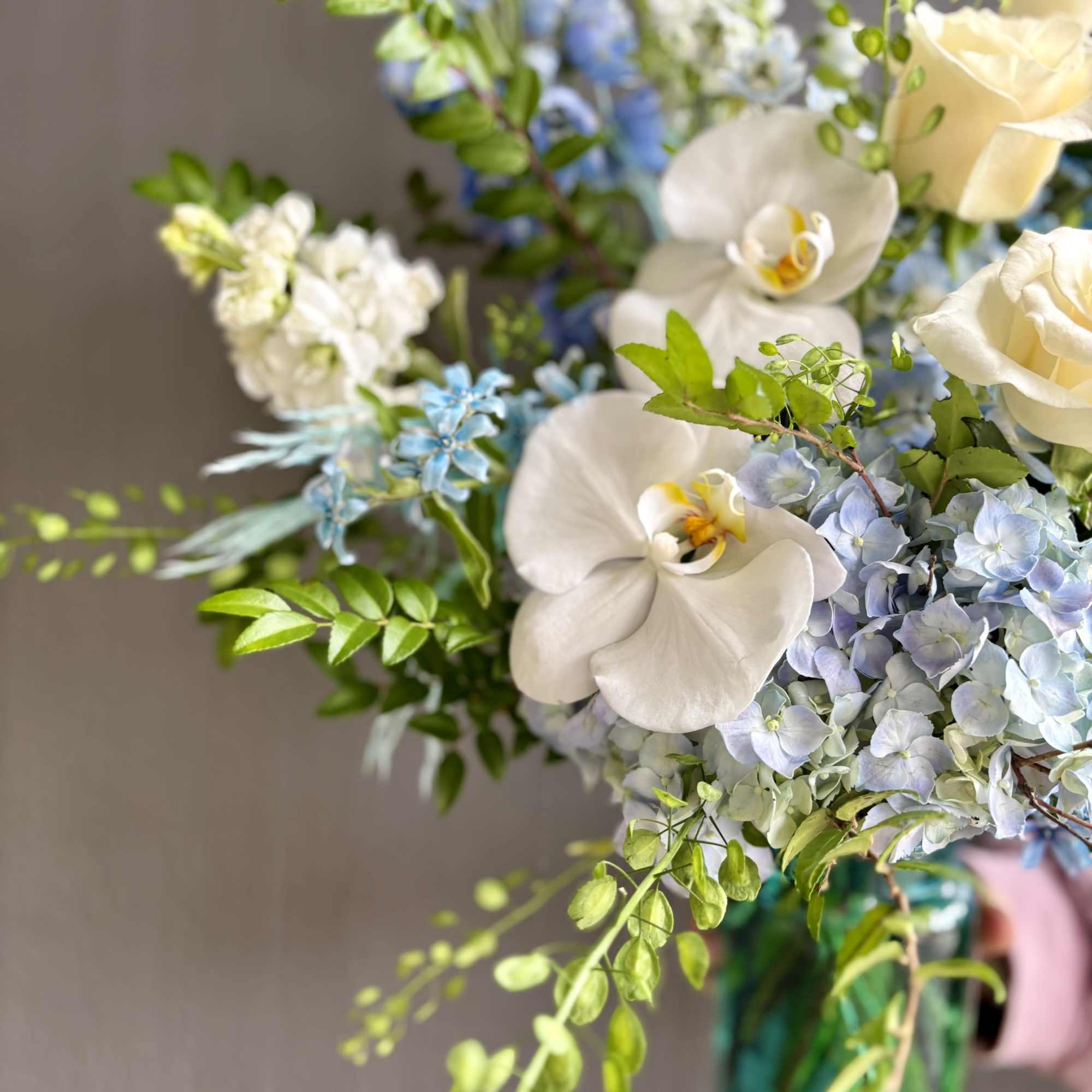 Aqua tones are refreshing in this arrangement. Featuring blue hydrangeas and delphiniums