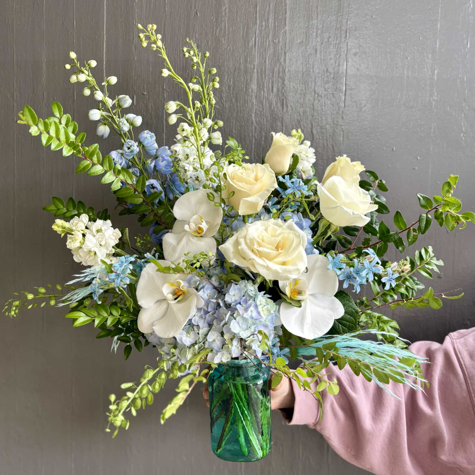 Aqua tones are refreshing in this arrangement. Featuring blue hydrangeas and delphiniums