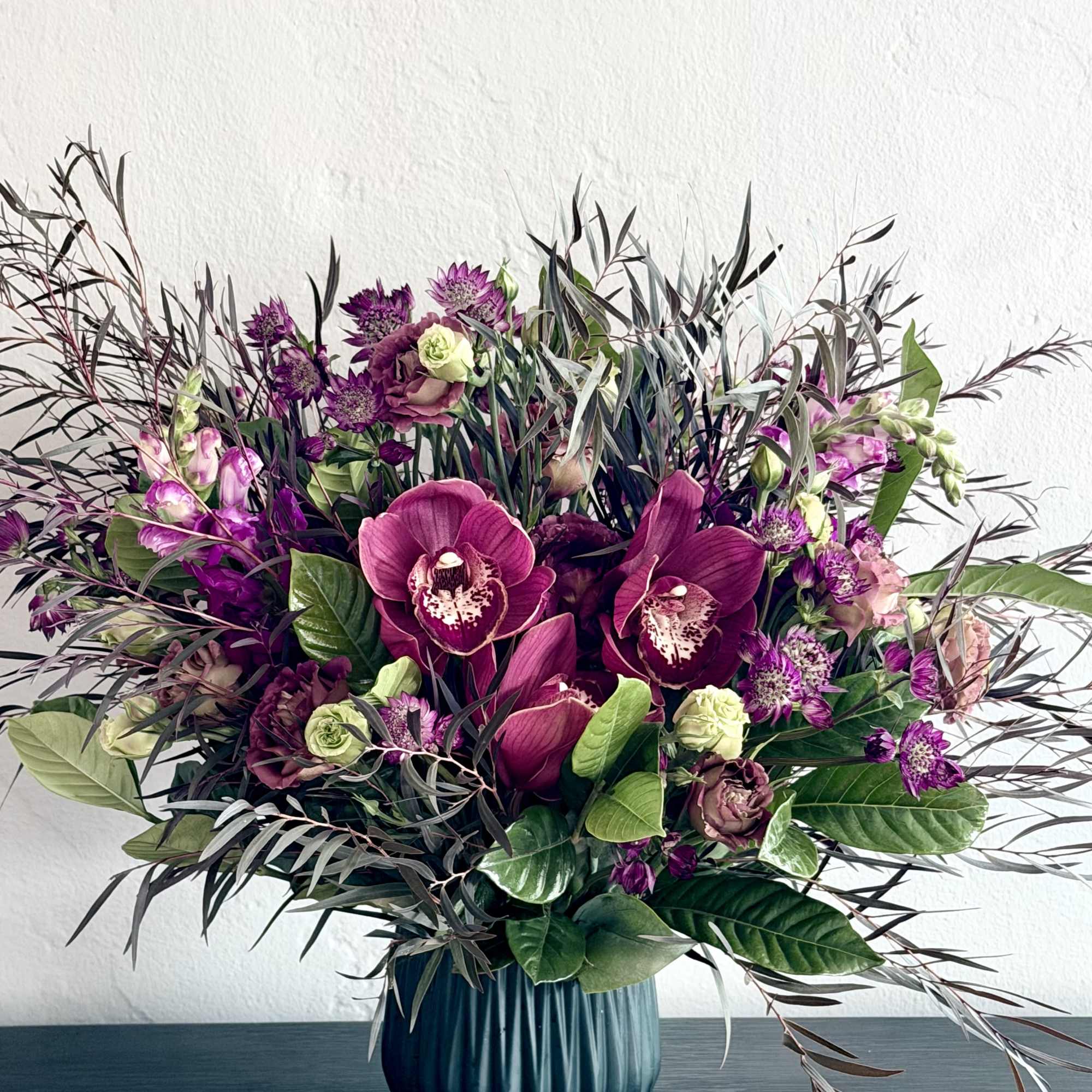 Unique and dramatic arrangement features richly colored maroon blooms! 