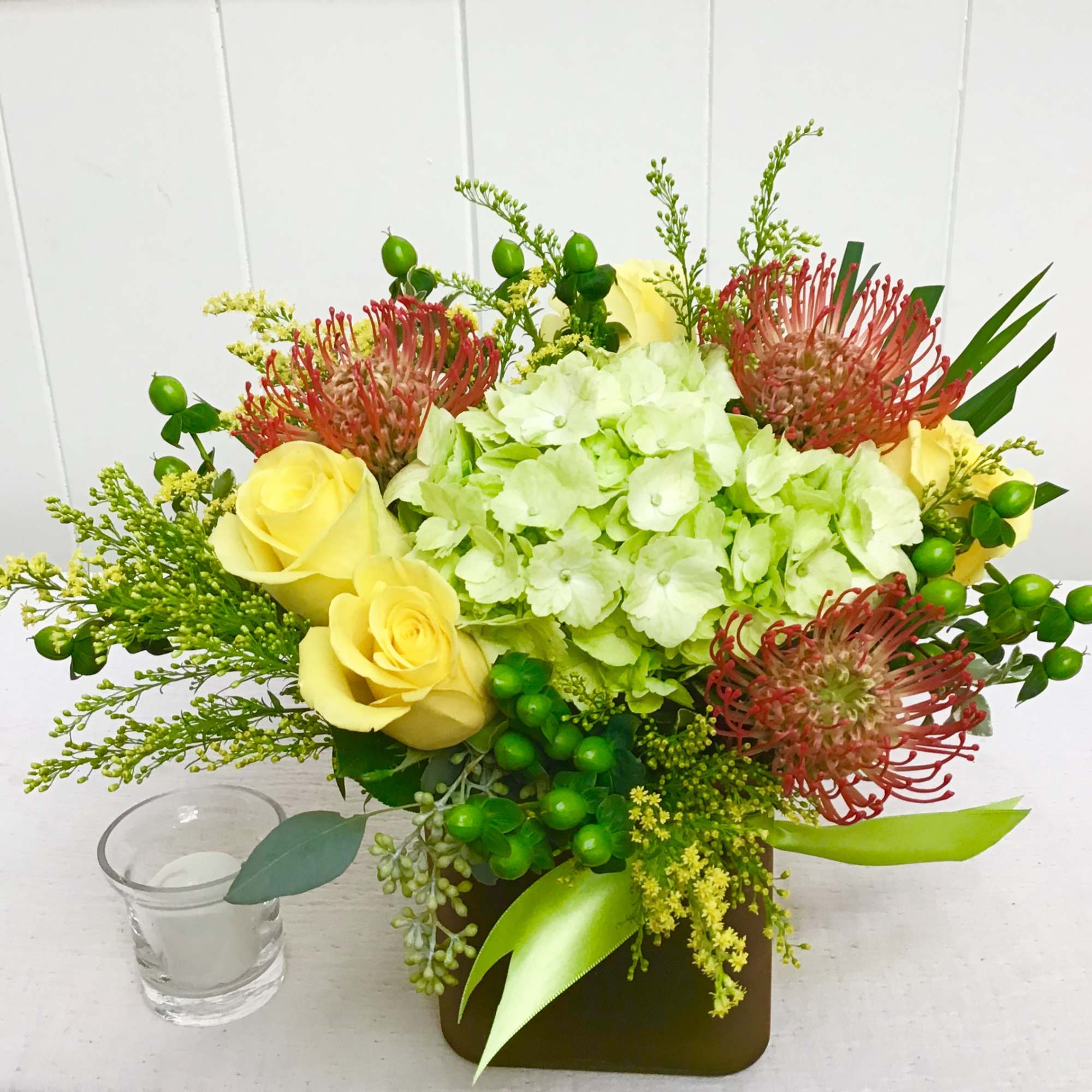 This fun colored cube has hydrangea, pin cushion protea and roses. 