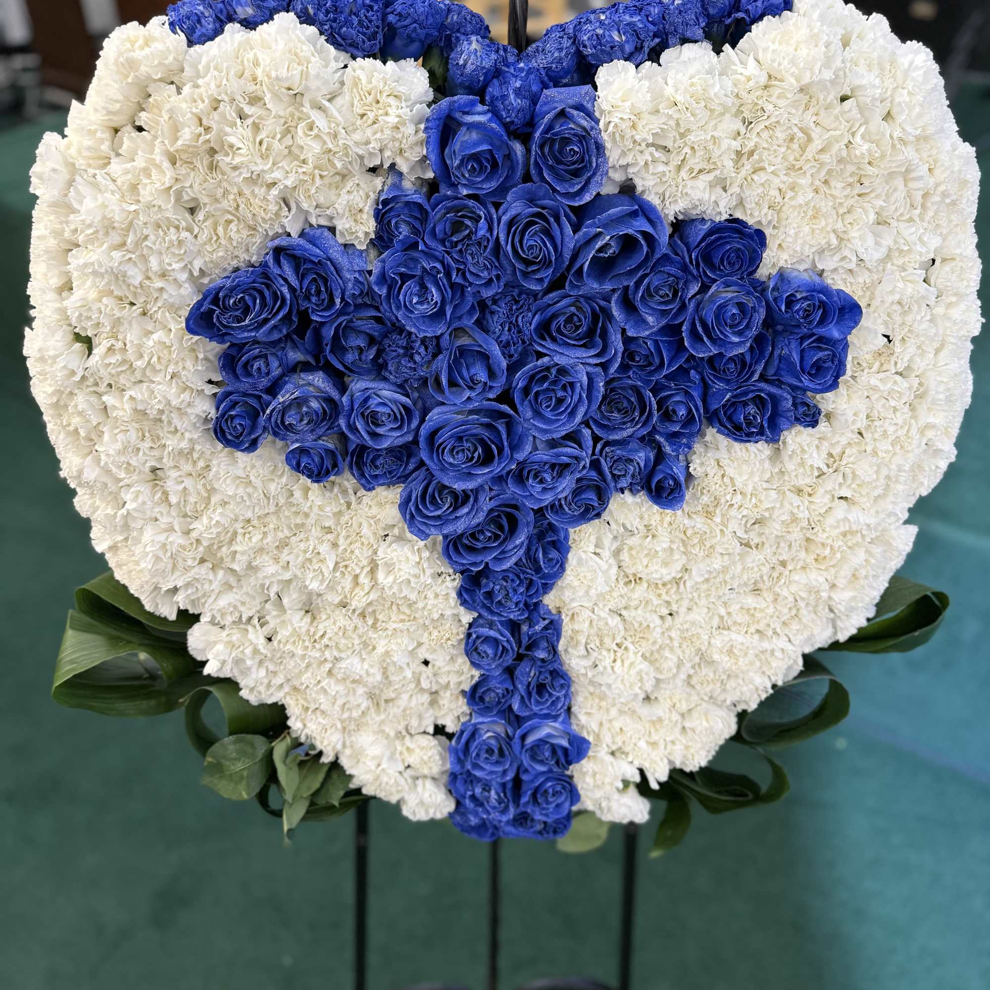 A heartfelt tribute of white carnations and royal blue roses forming a