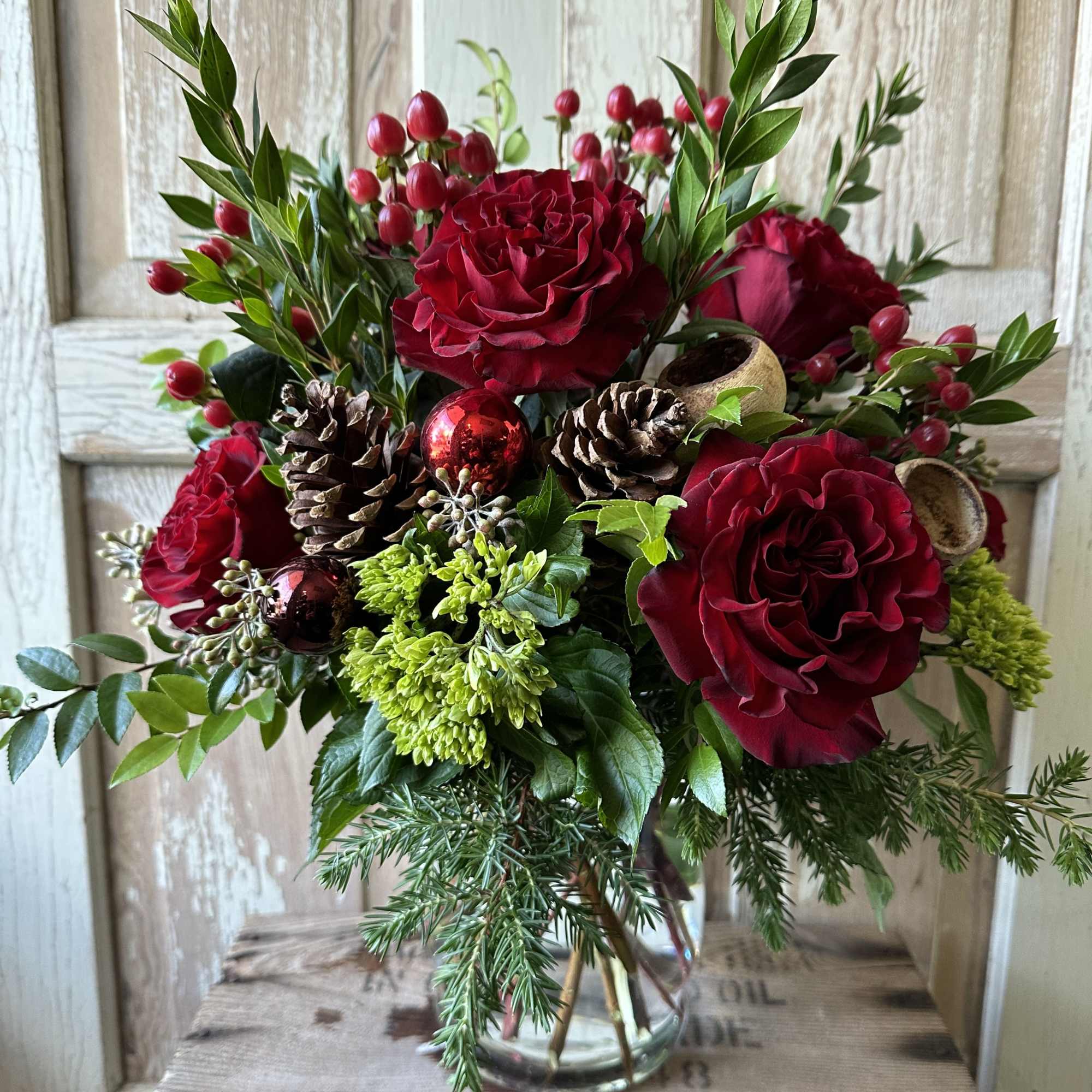 Warm up any home with this festive holiday arrangement! Seasonal fragrant greens