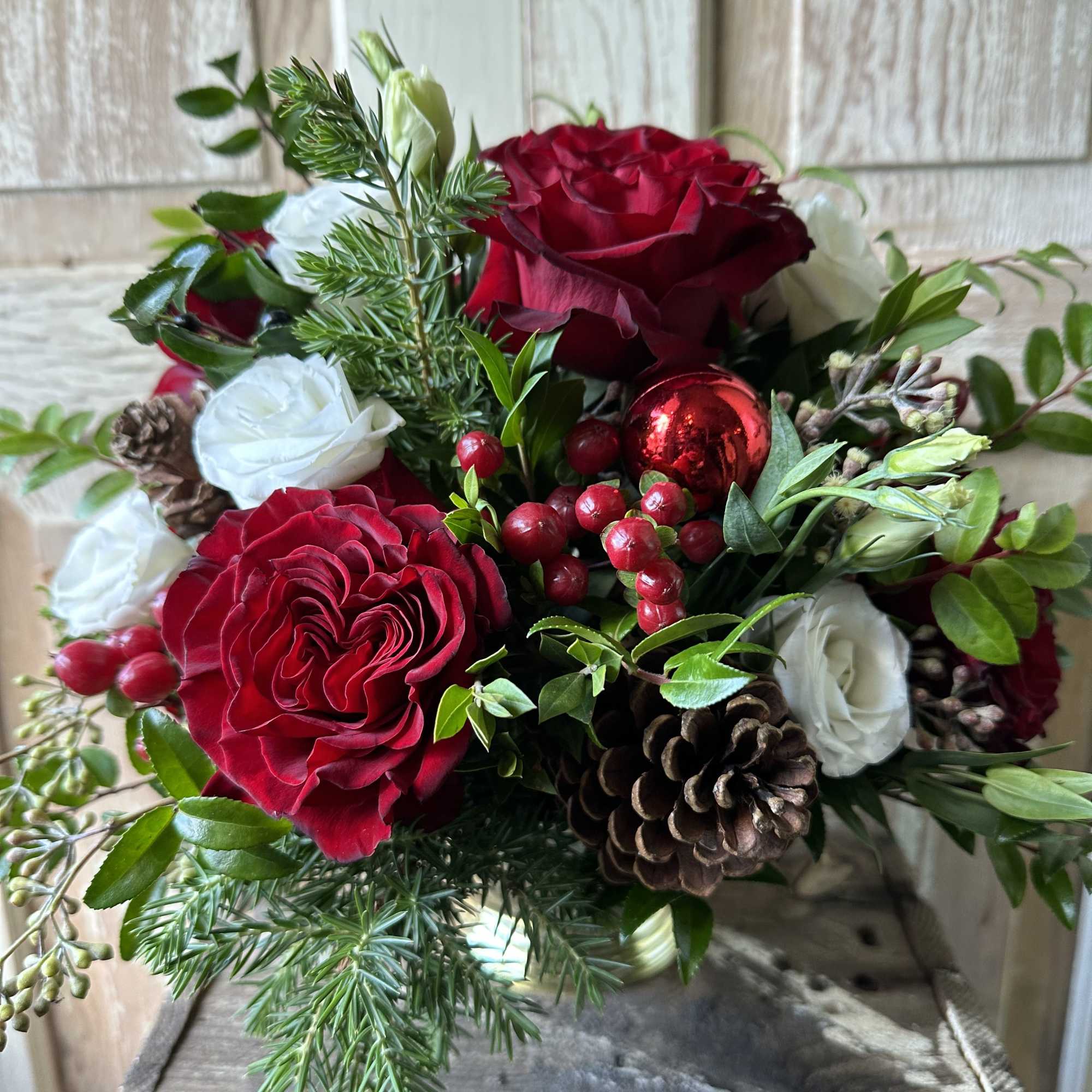 A perfect table centerpiece filled with roses, lisianthus, red hypericum berries and