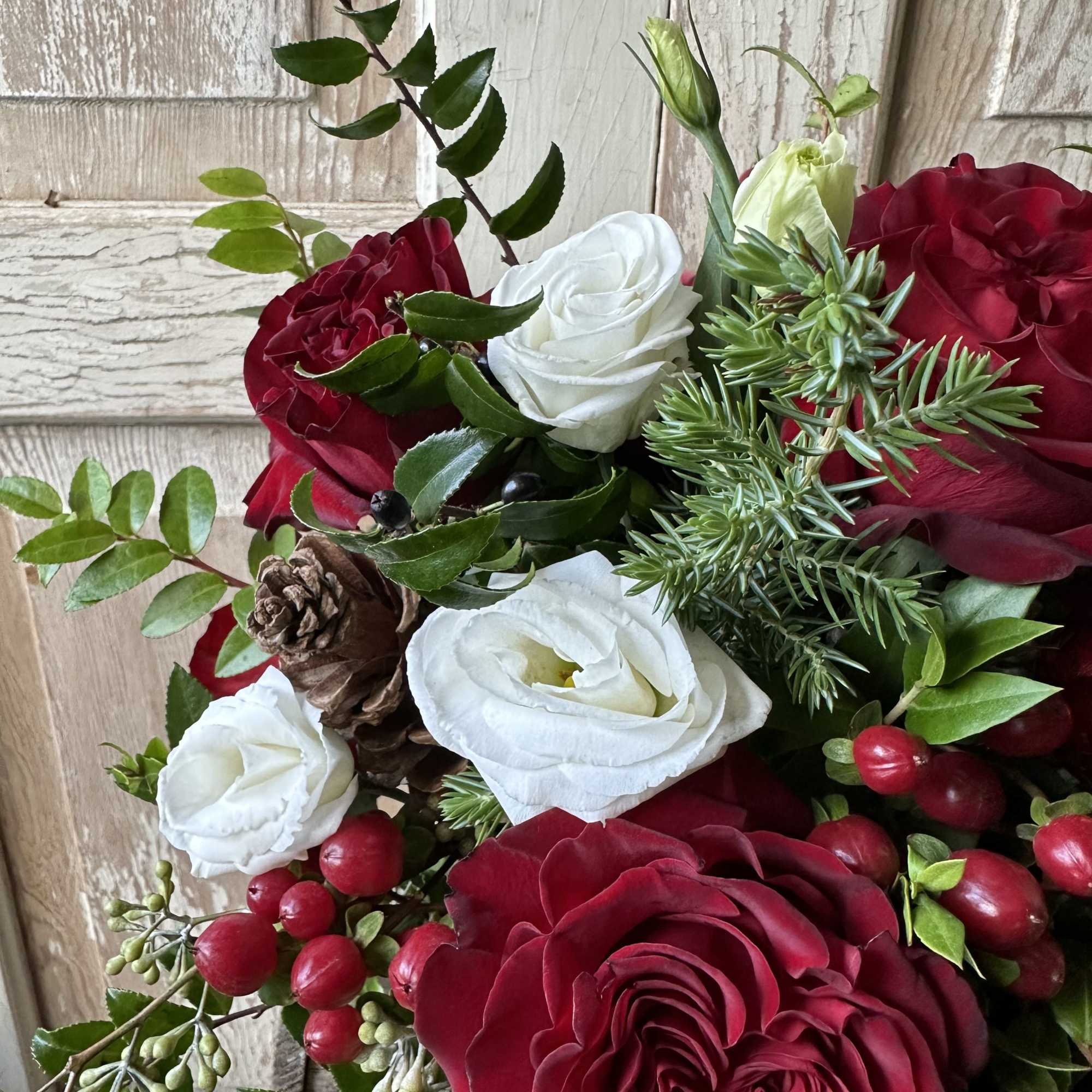 A perfect table centerpiece filled with roses, lisianthus, red hypericum berries and