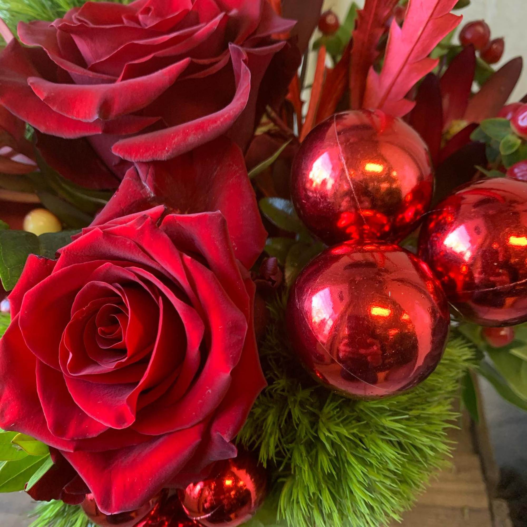 A festive Display of seasonal red roses, berries, balls and evergreens
