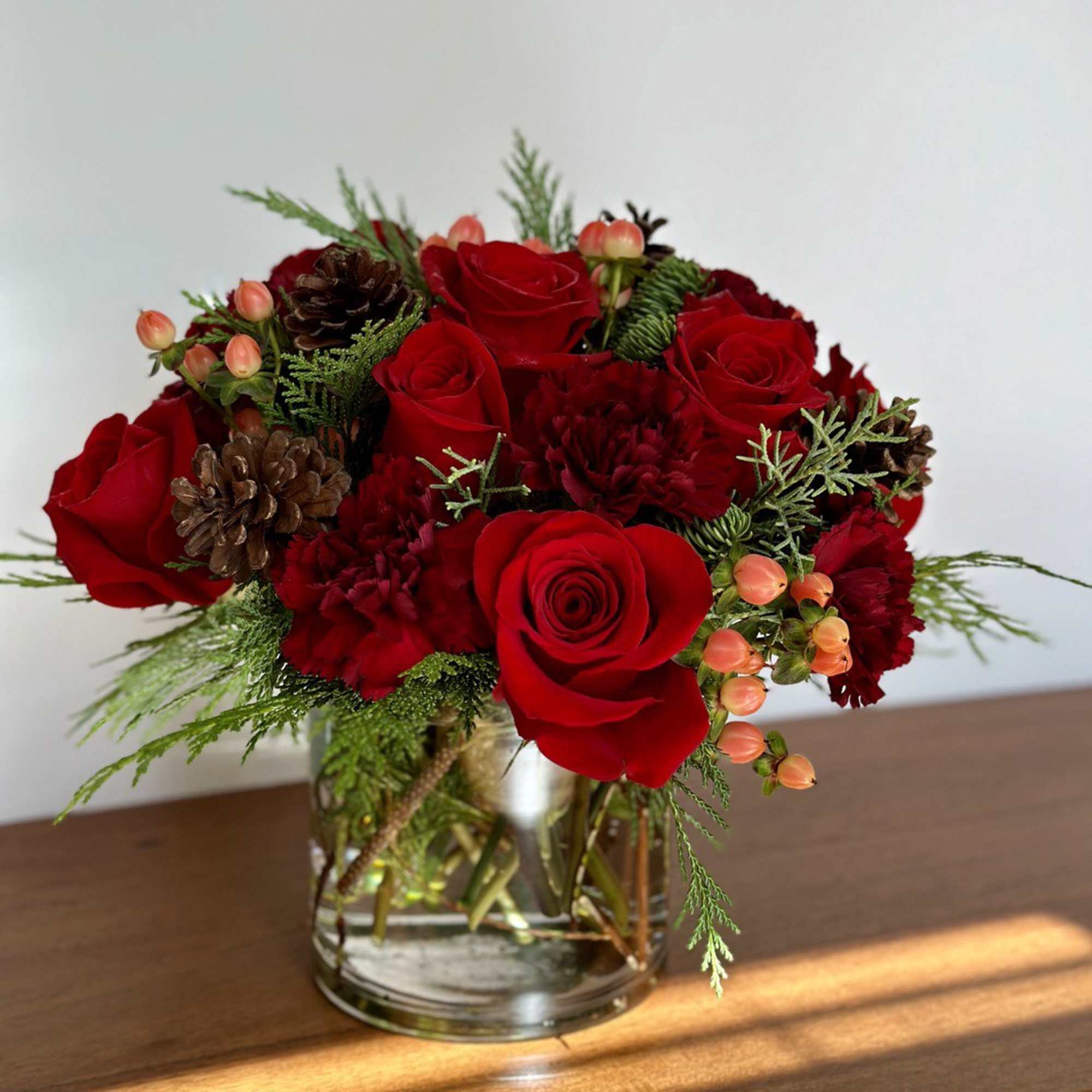 The winter flower arrangement features vibrant red roses and carnations accented with