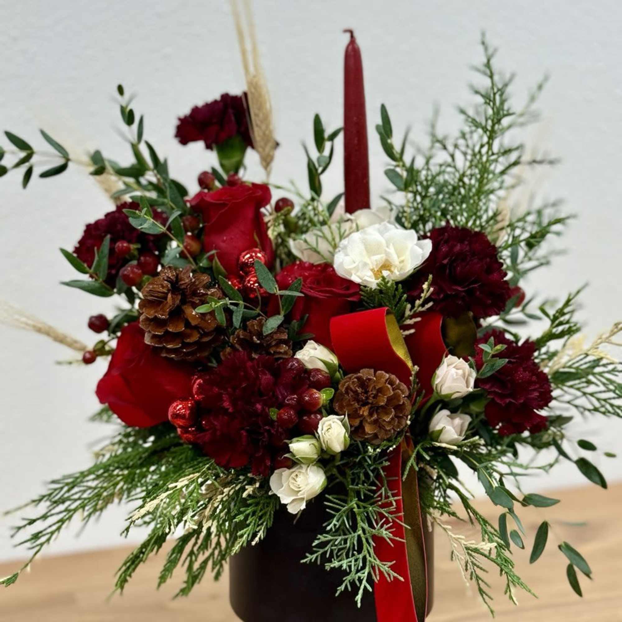 A lovely Christmas arrangement enhanced by a red candle made in a