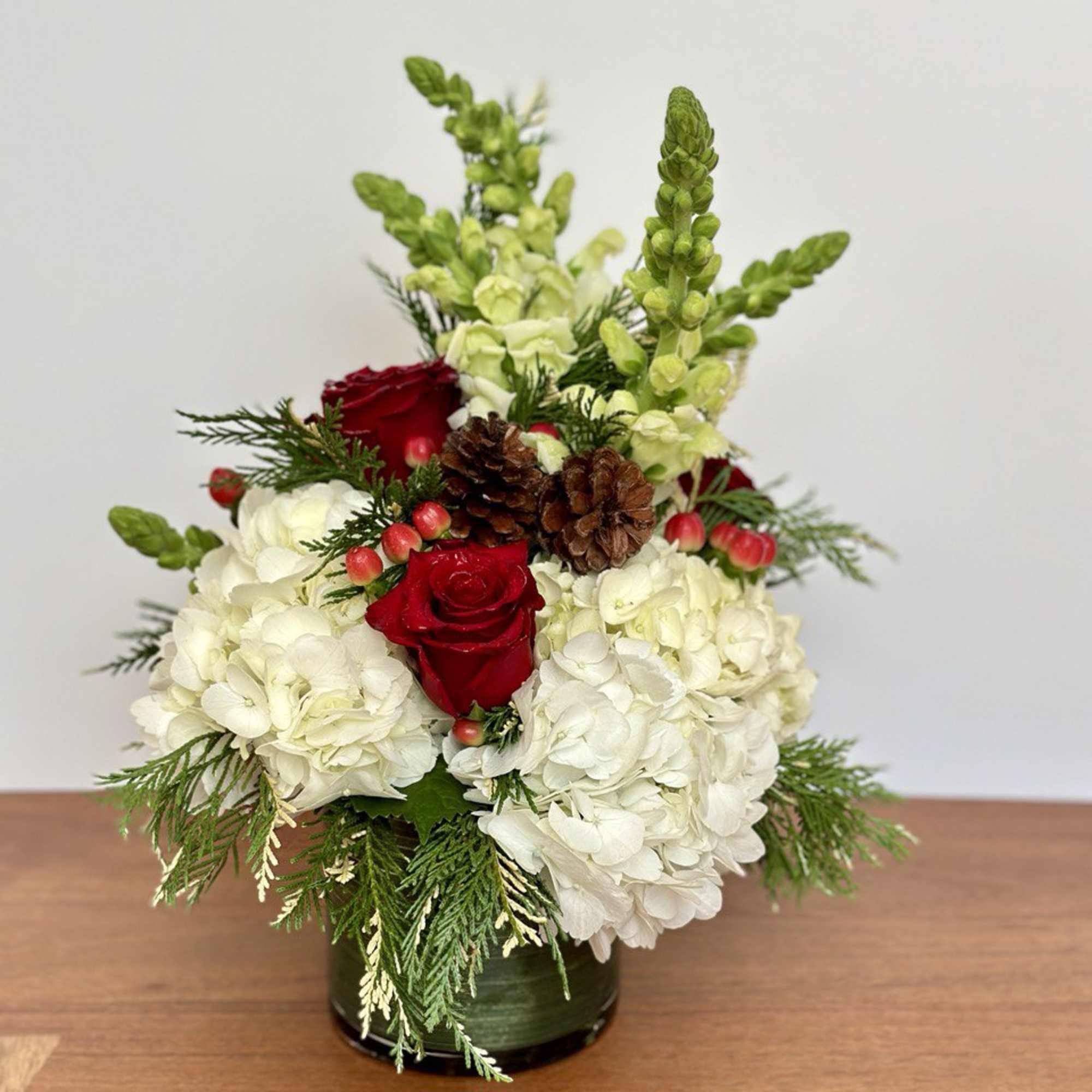 A festive Christmas centerpiece with holiday greenery and pine cones, delivered in