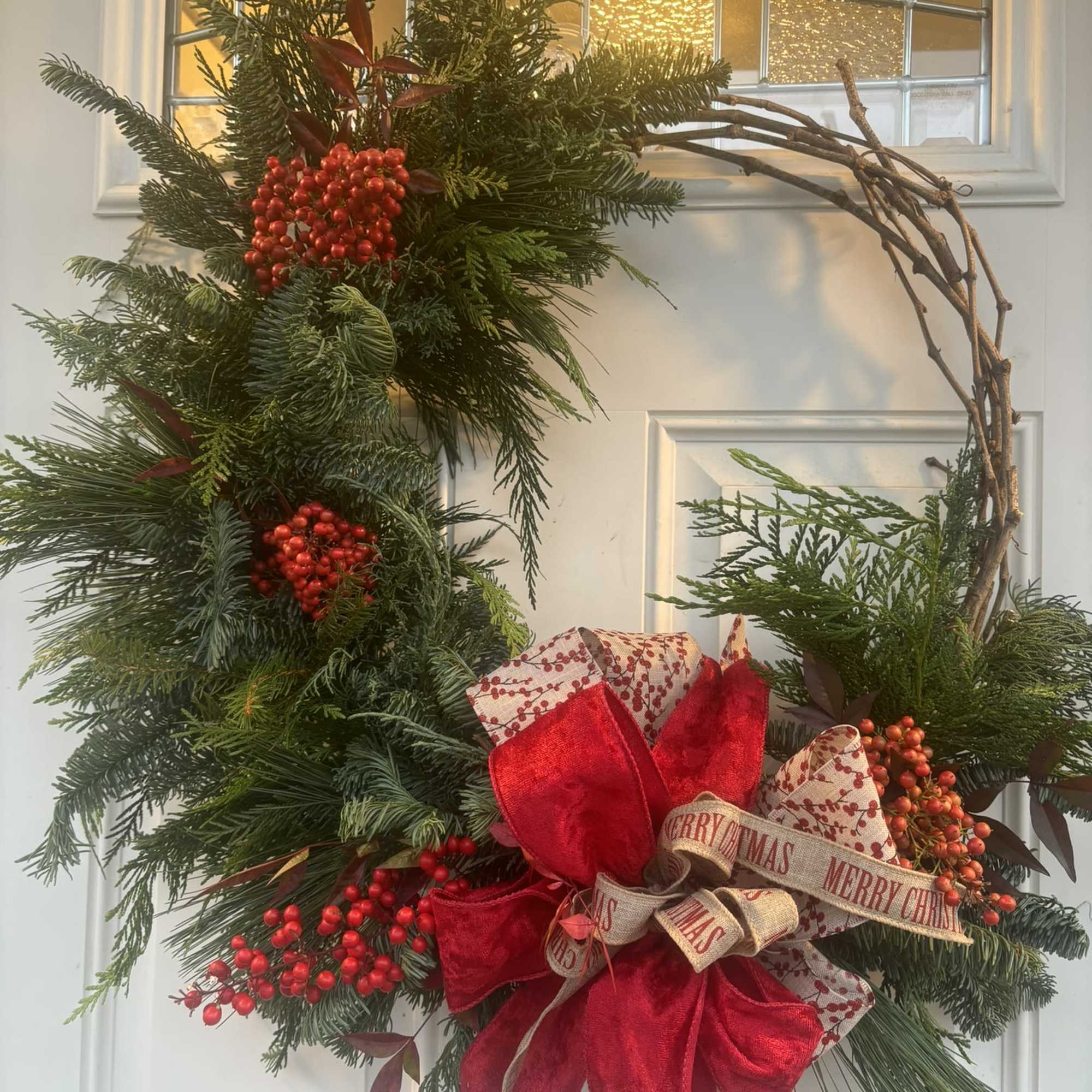 A 10&quot; grapevine wreath with a variety of fresh evergreens, ferns, seed