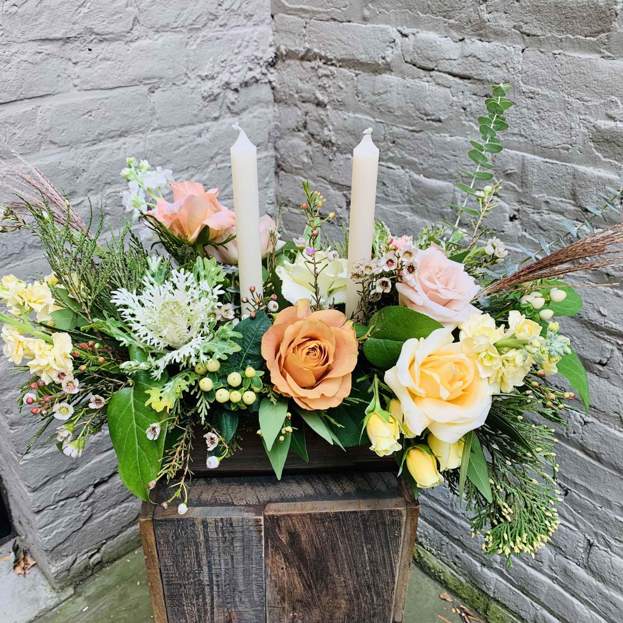 An exquisite long and low centerpiece arrangement with glowing tapers and blooms