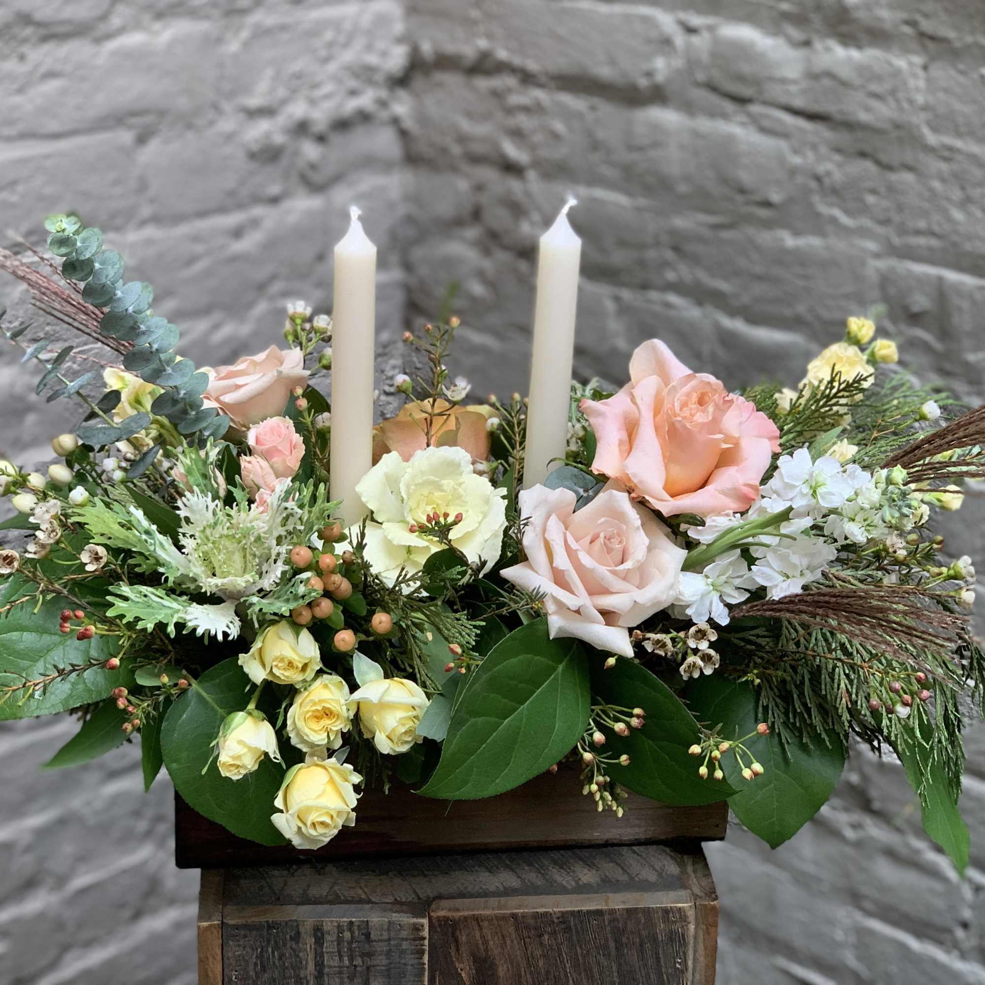 An exquisite long and low centerpiece arrangement with glowing tapers and blooms