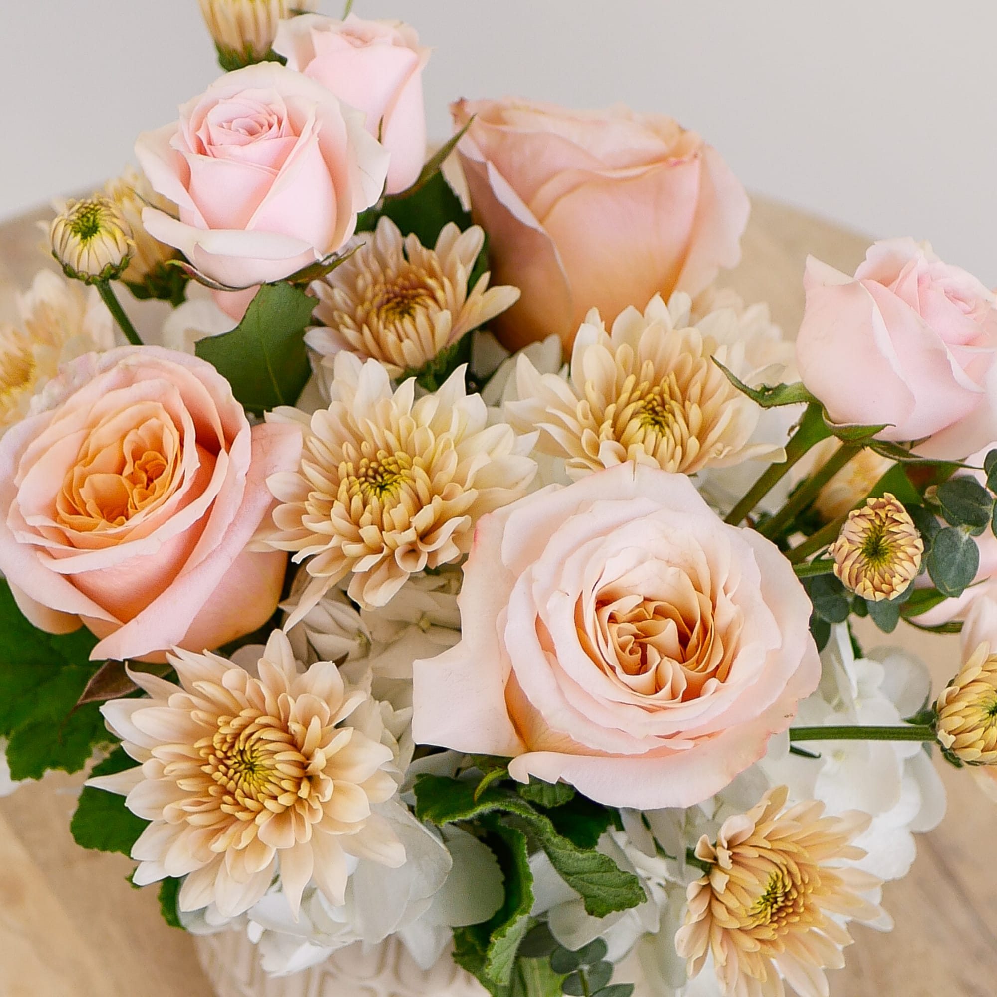 This darling arrangement features a soft peach design with hydrangeas, roses, mums