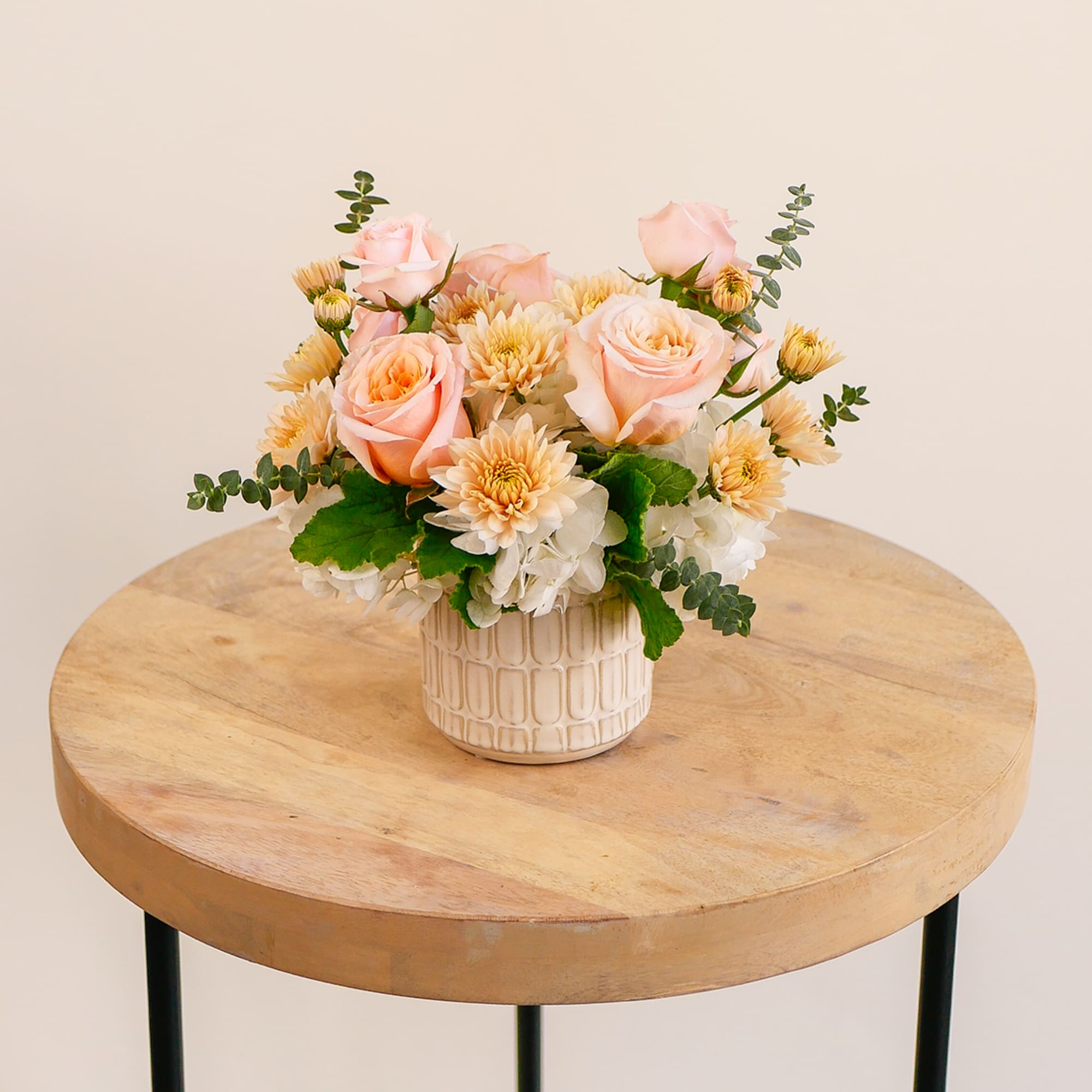 This darling arrangement features a soft peach design with hydrangeas, roses, mums