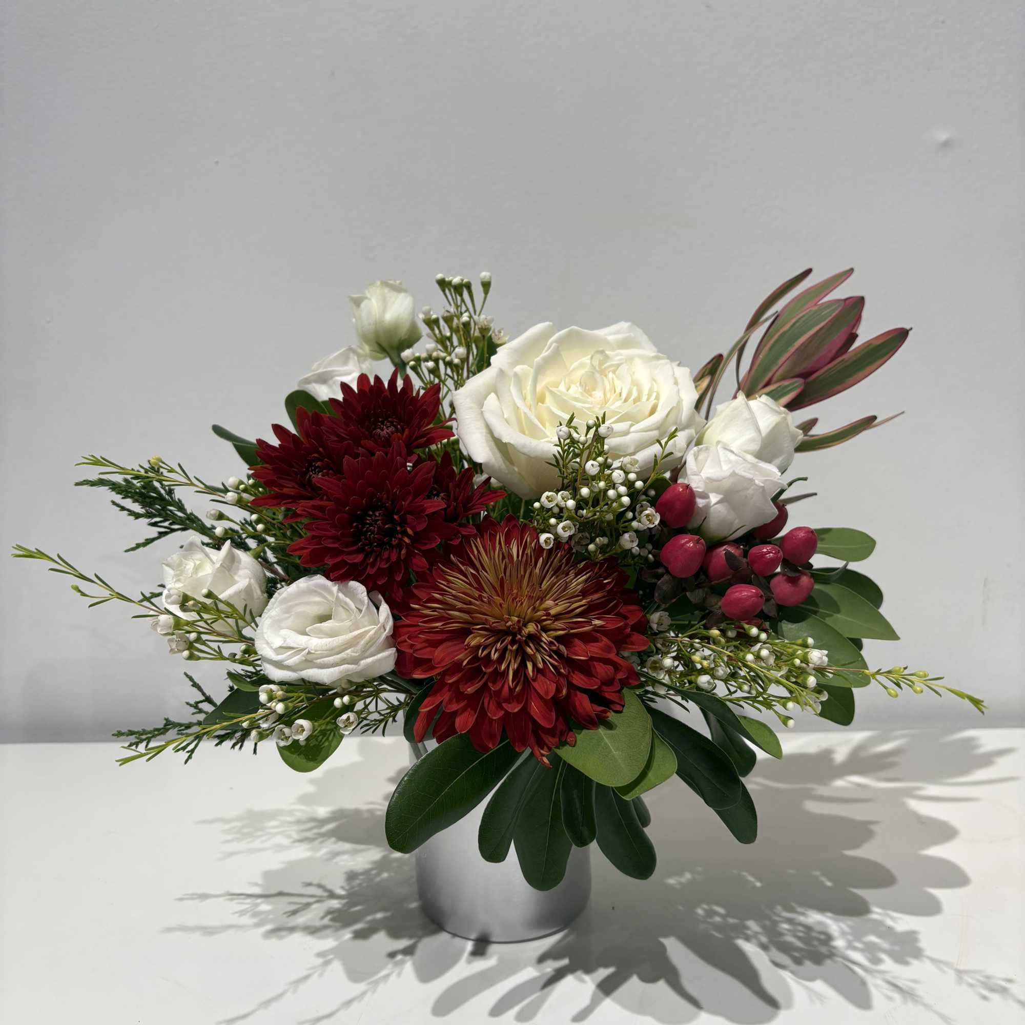 A glass cup holding an array of fresh cut Florals in seasonal