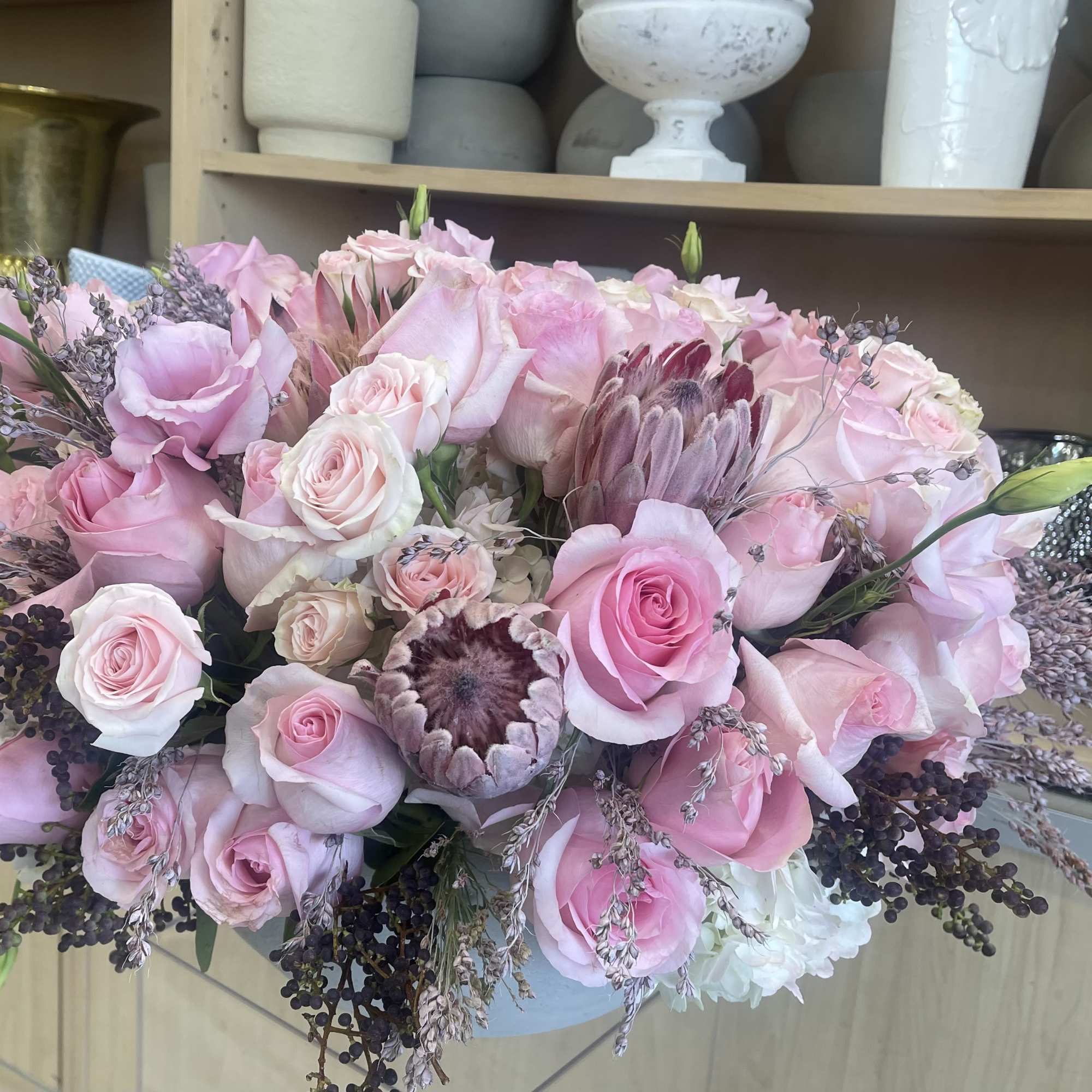 A romantic mix of soft pink roses, protea, and delicate lisianthus, accented