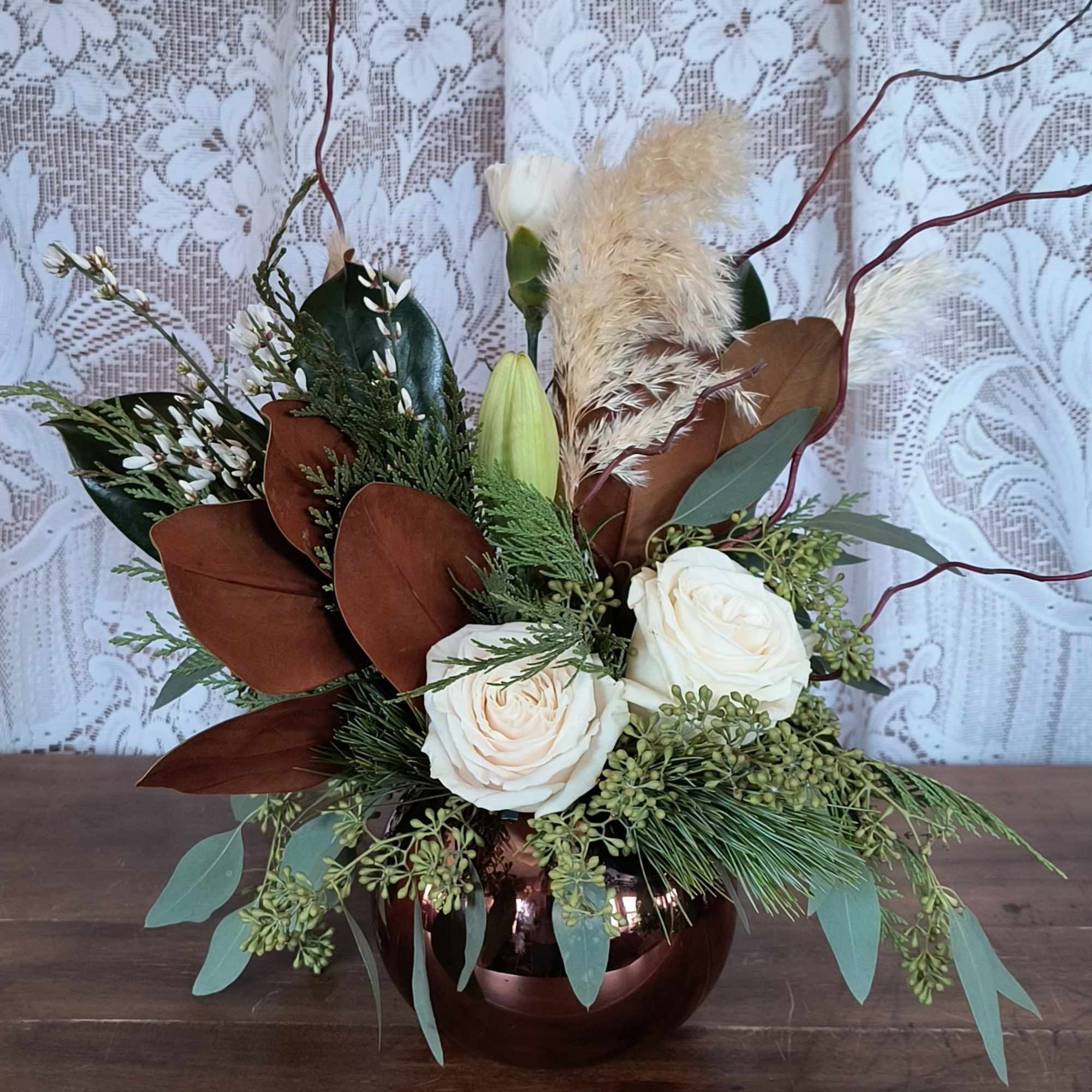 This winter arrangement brings serene holiday beauty with snowy white blooms, frosted