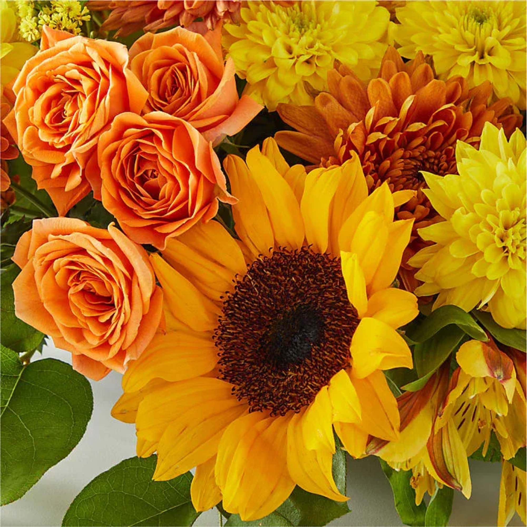 Warm sunflowers, amber mums, and glowing roses come together around twin taper