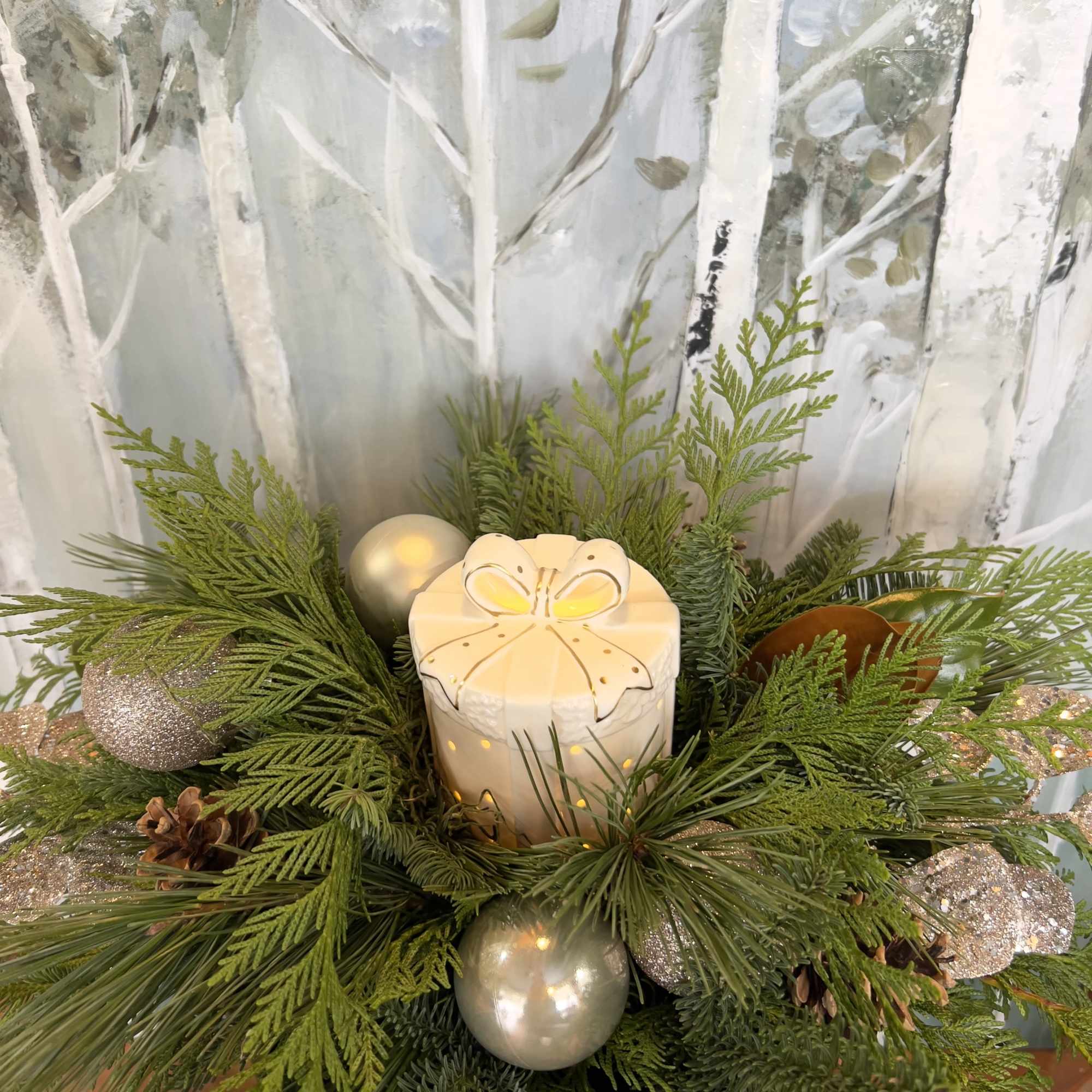 This arrangement incorporates a ceramic holiday present with a soft warm glow