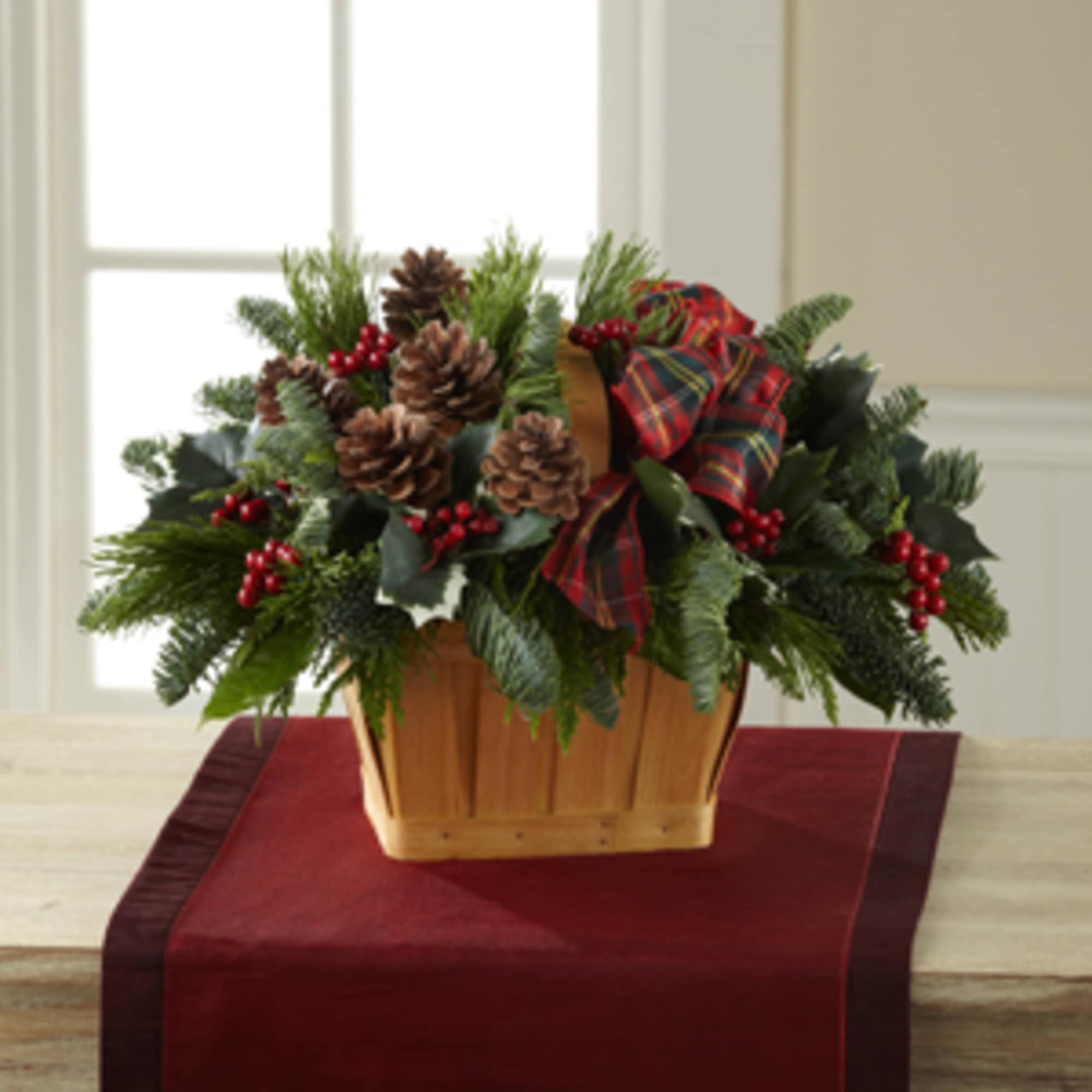 This natural wooden basket is filled with fragrant winter greens, pine cones