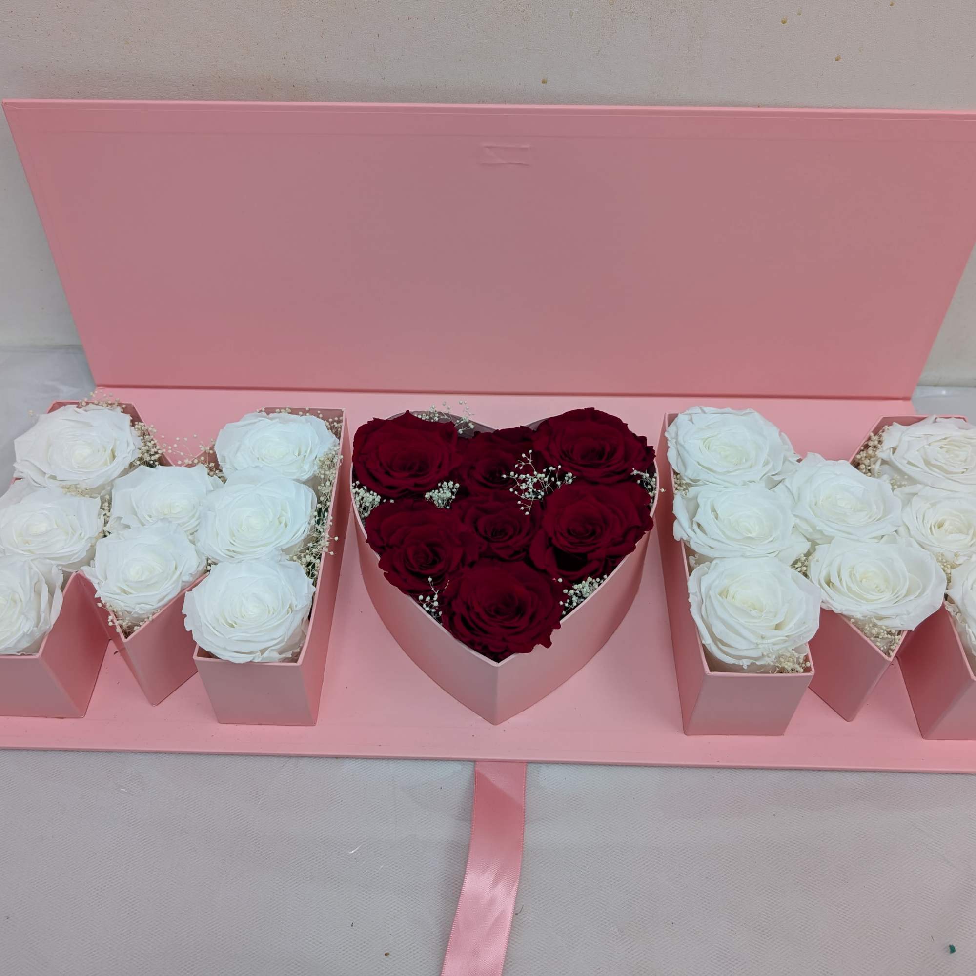 White and red preserved roses in a pink gift Box.