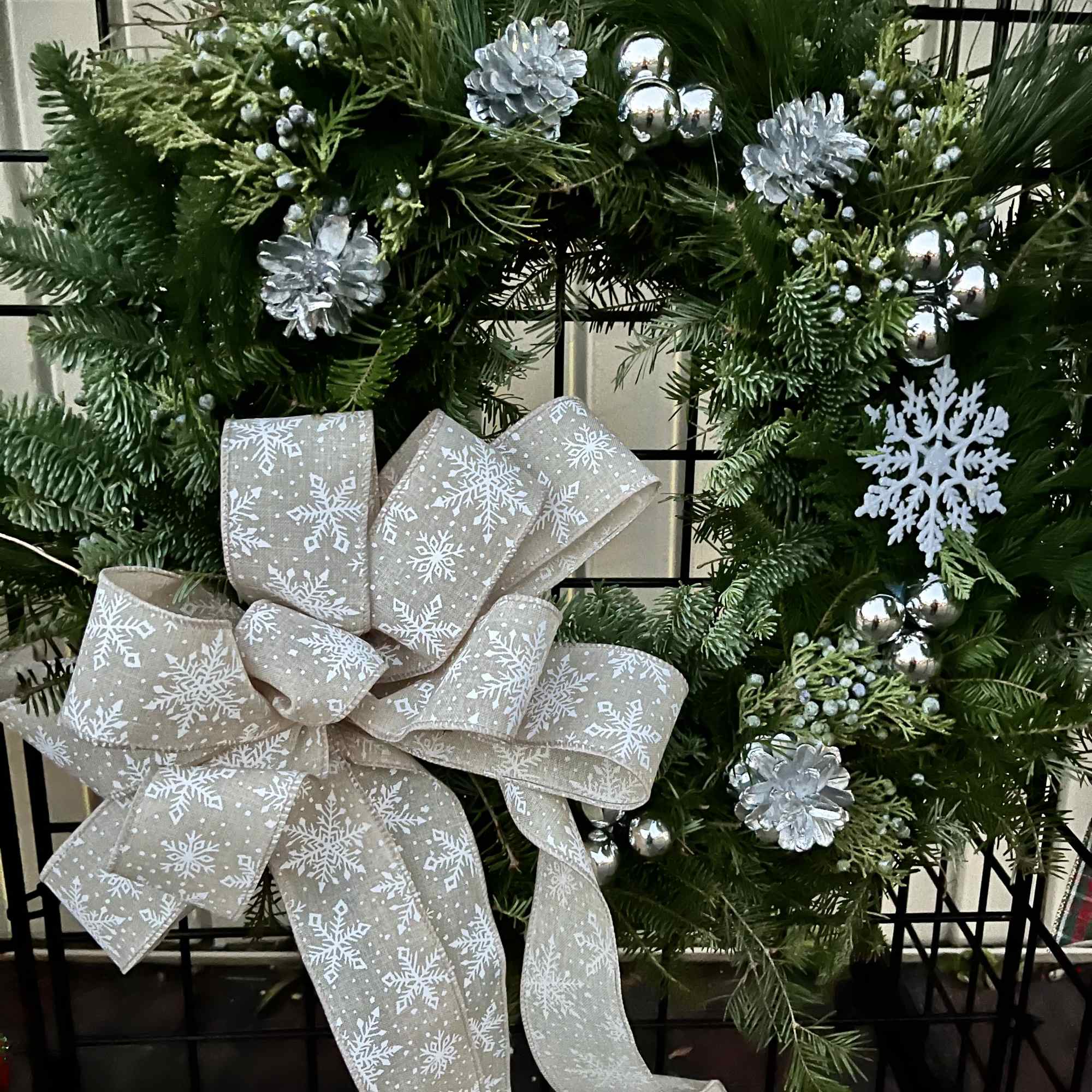 A door wreath with traditional decorations of a red velvet bow, pine