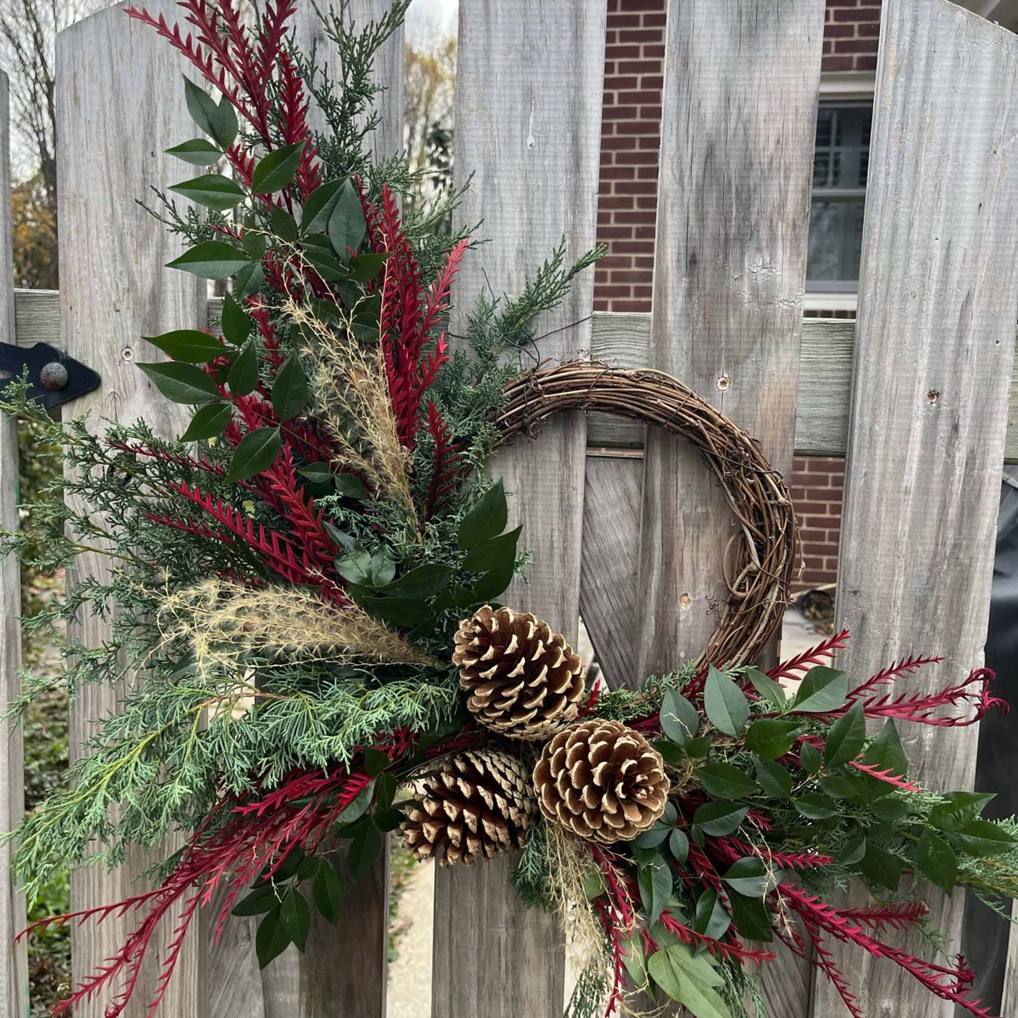 A 10&quot; grapevine wreath with a variety of fresh evergreens, ferns, seed