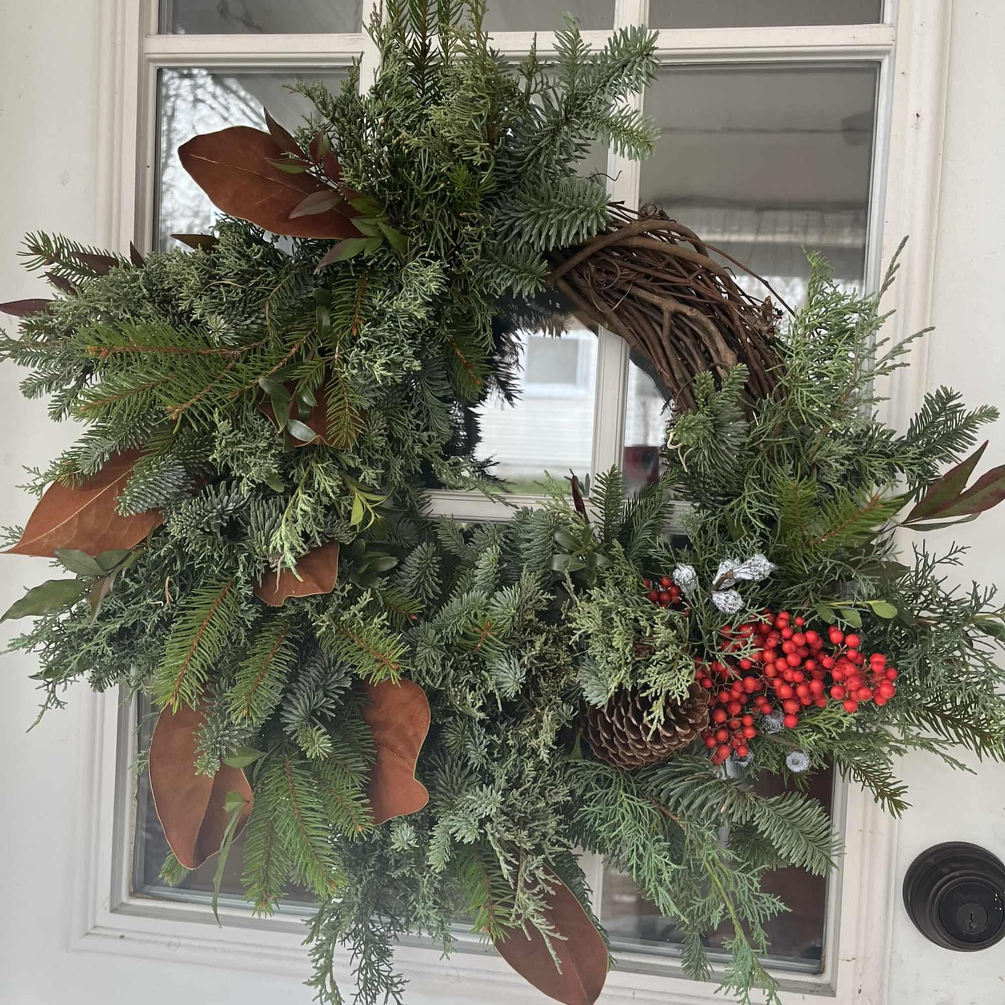 A 10&quot; grapevine wreath with a variety of fresh evergreens, ferns, seed