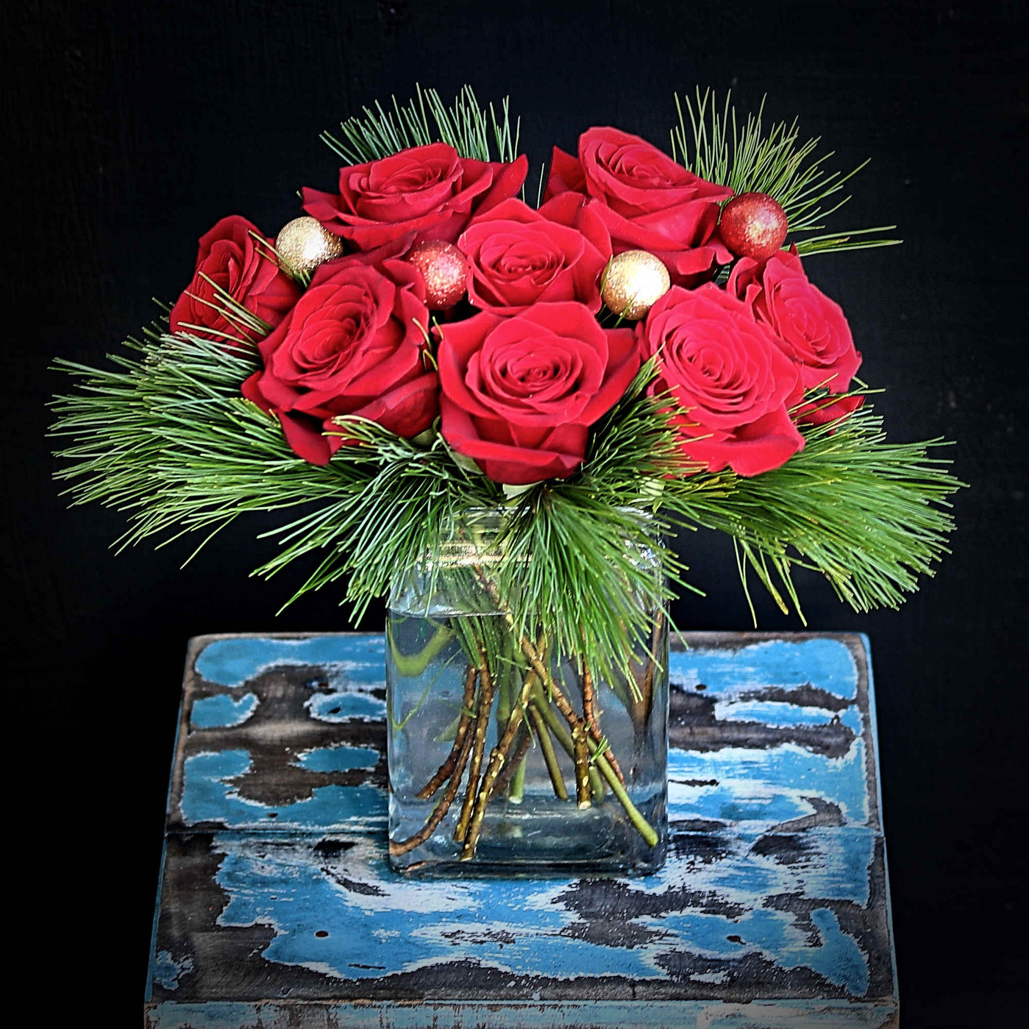 One dozen of red roses with Christmas greens and ornaments in a