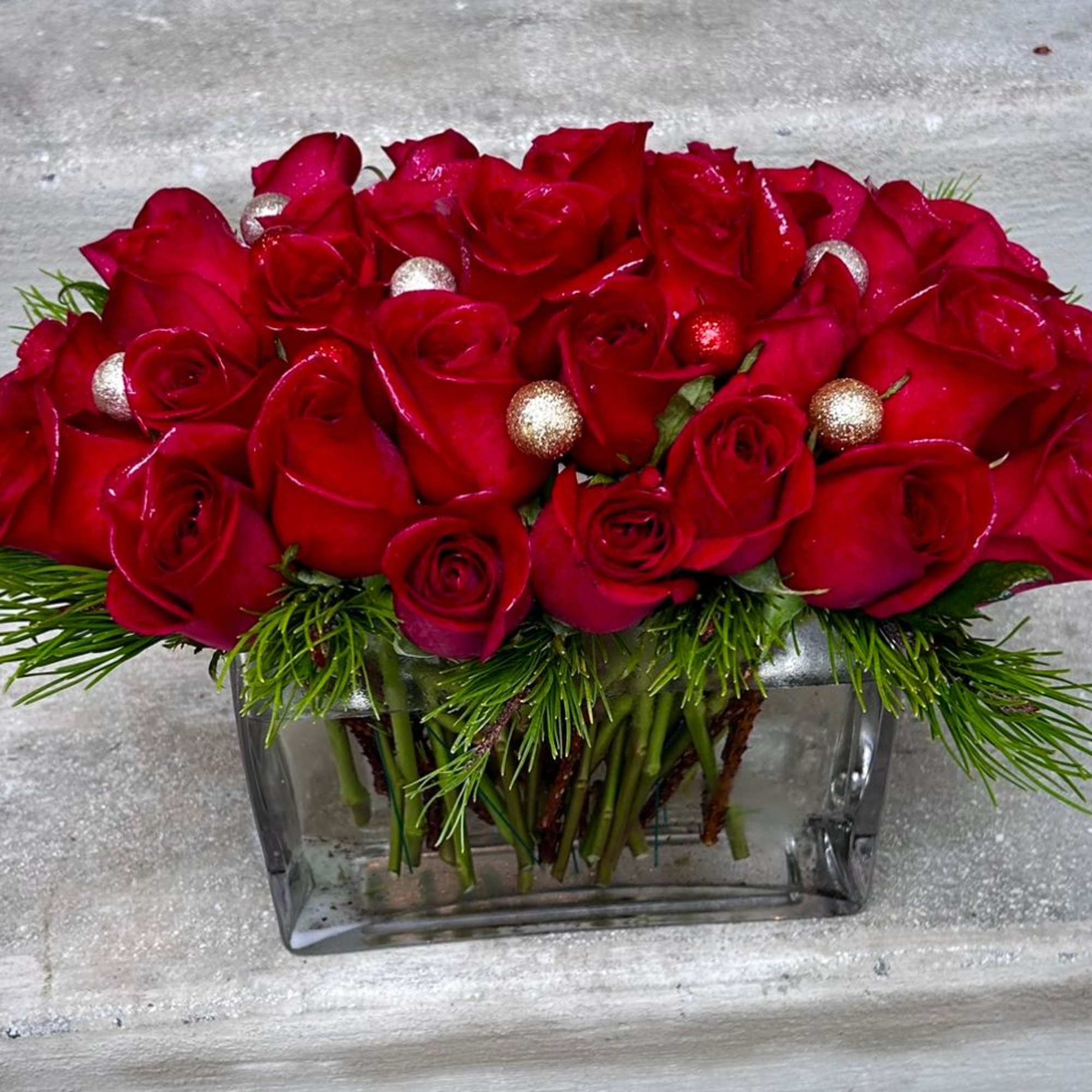 One dozen of red roses with Christmas greens and ornaments in a