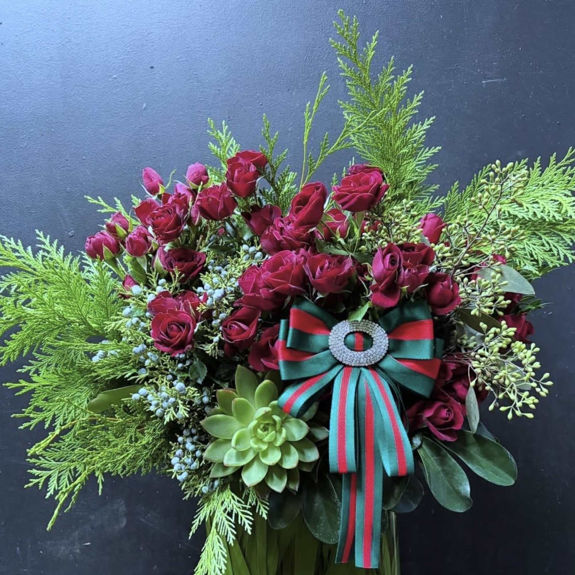 Red garden spray roses, holiday greens, ribbon that can also be worn