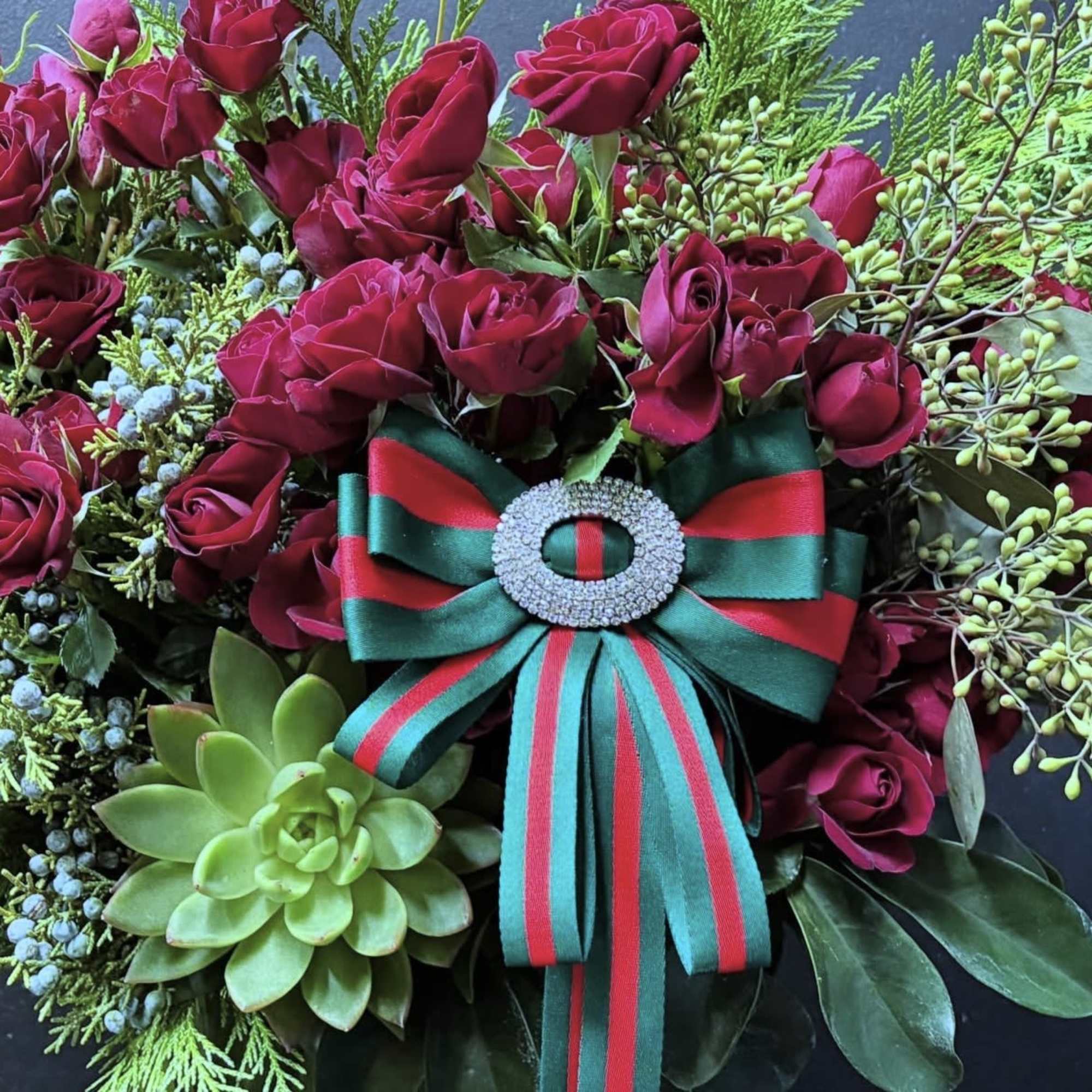 Red garden spray roses, holiday greens, ribbon that can also be worn