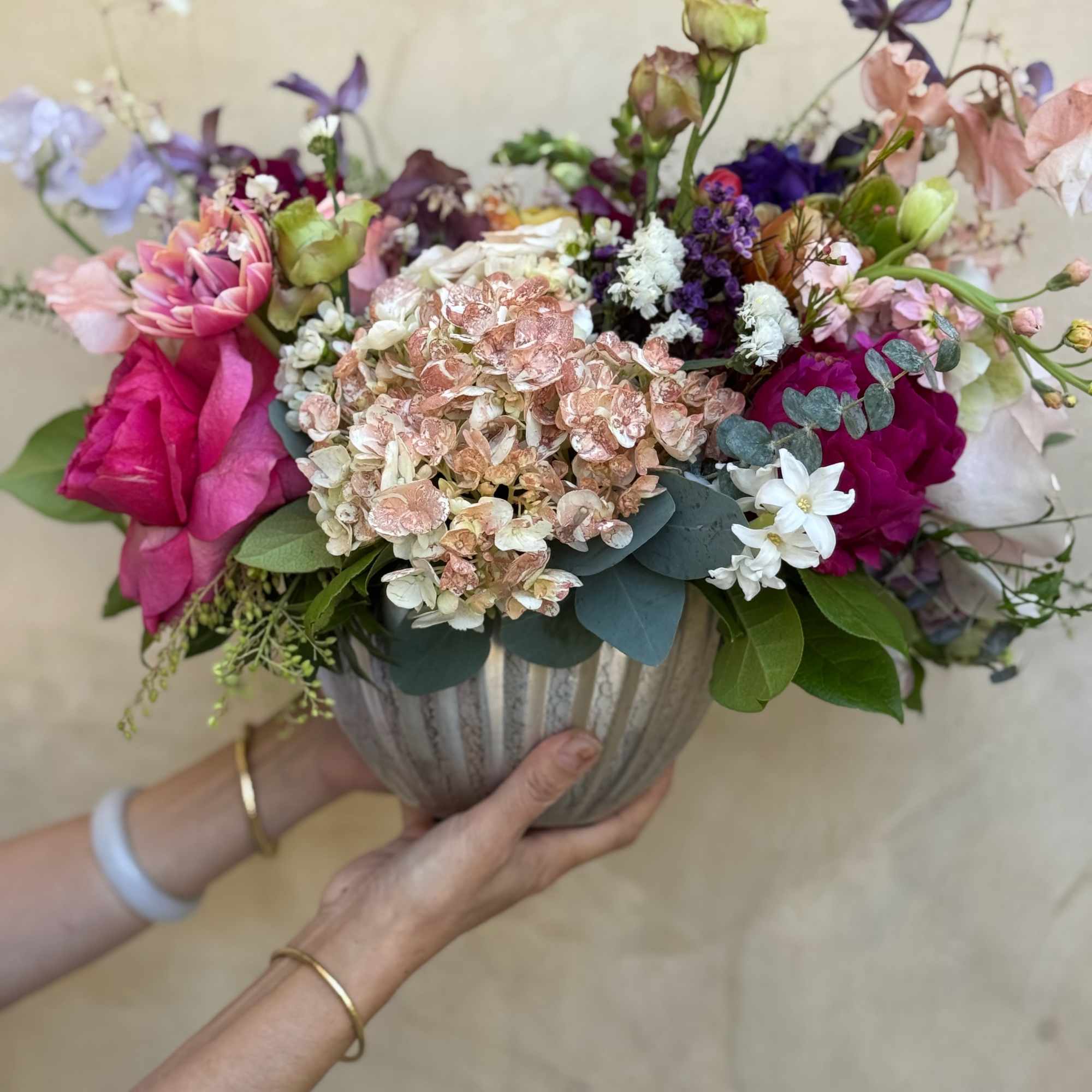 A lush, garden-style arrangement featuring hydrangeas, garden roses ranunculus, sweet peas, lisianthus