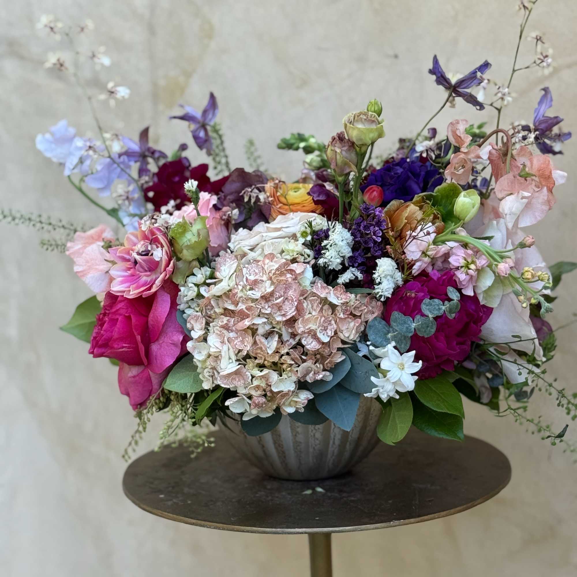 A lush, garden-style arrangement featuring hydrangeas, garden roses ranunculus, sweet peas, lisianthus